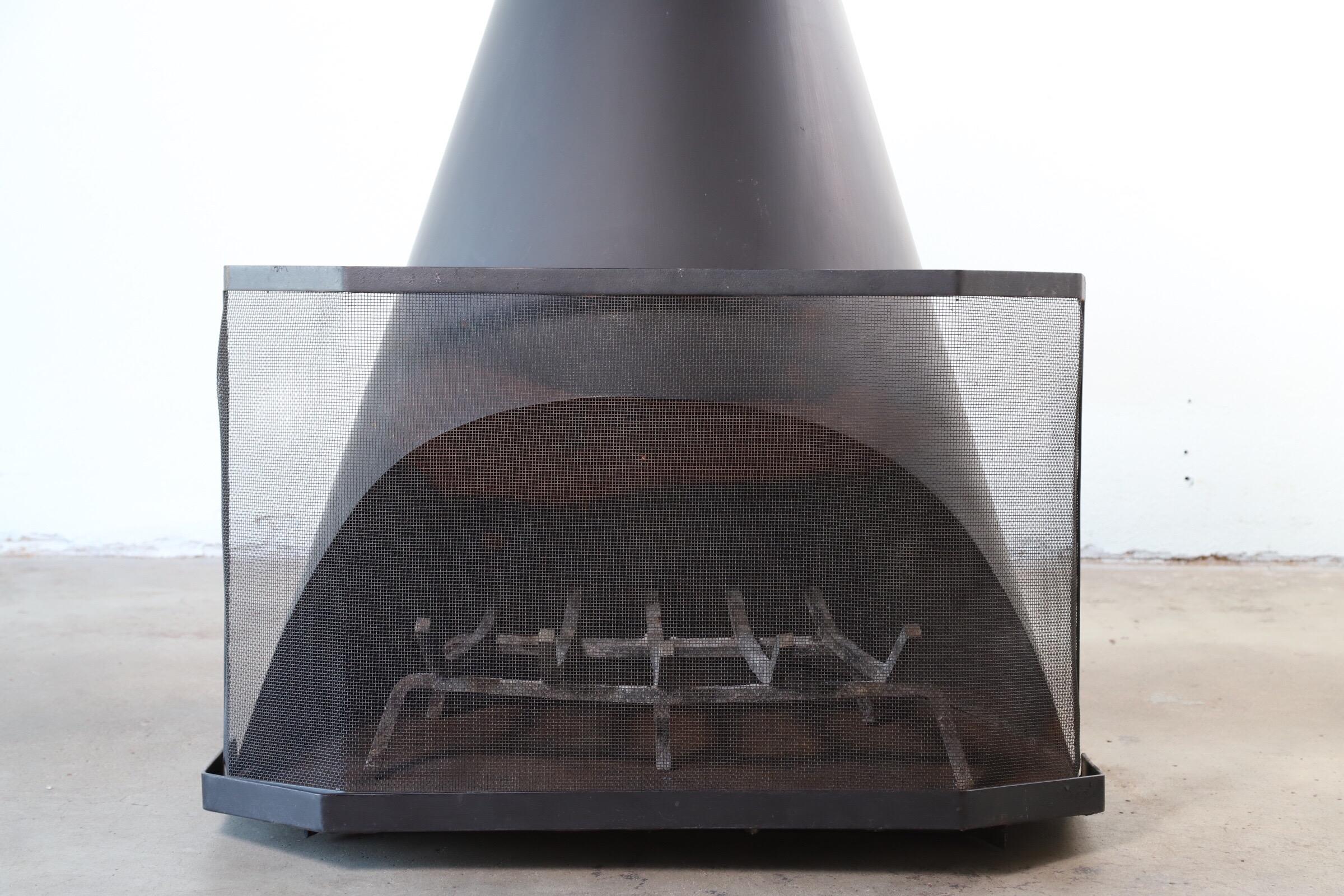 1960s steel indoor or outdoor cone shaped fireplace with rack and screen. Designed and manufactured by Dick Heldenbrand (1928-2017) with his company Emberbox. This is a salvaged item. Heat resistant tube and exterior tube with vent lid available,