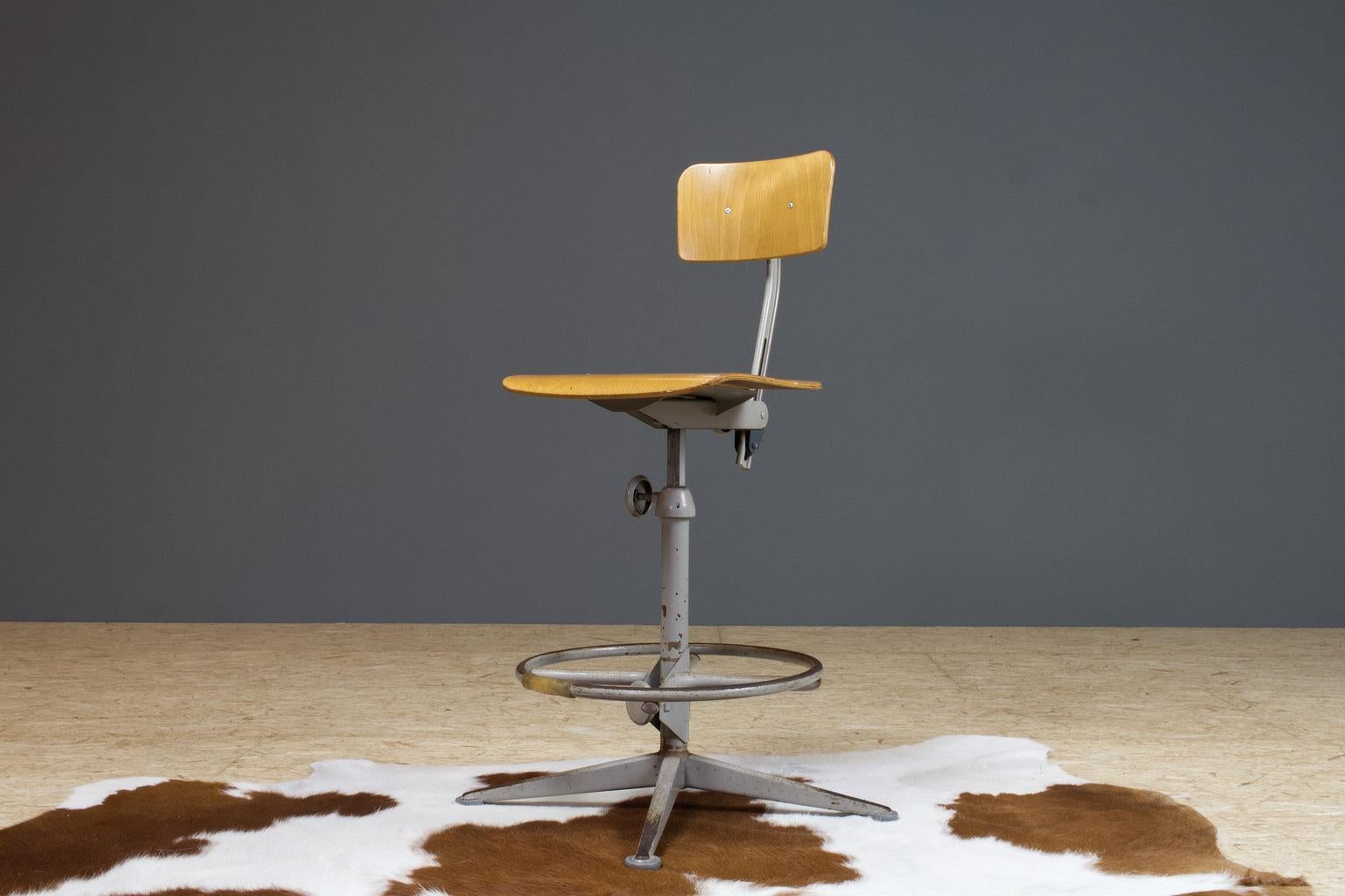 1963 Dutch Friso Kramer drawing board or architect chair by Ahrend de Cirkel. Light brown plywood and grey metal, adjustable in height and rotatable. This piece has a circular footrest, which is less common and therefor a great detail to this
