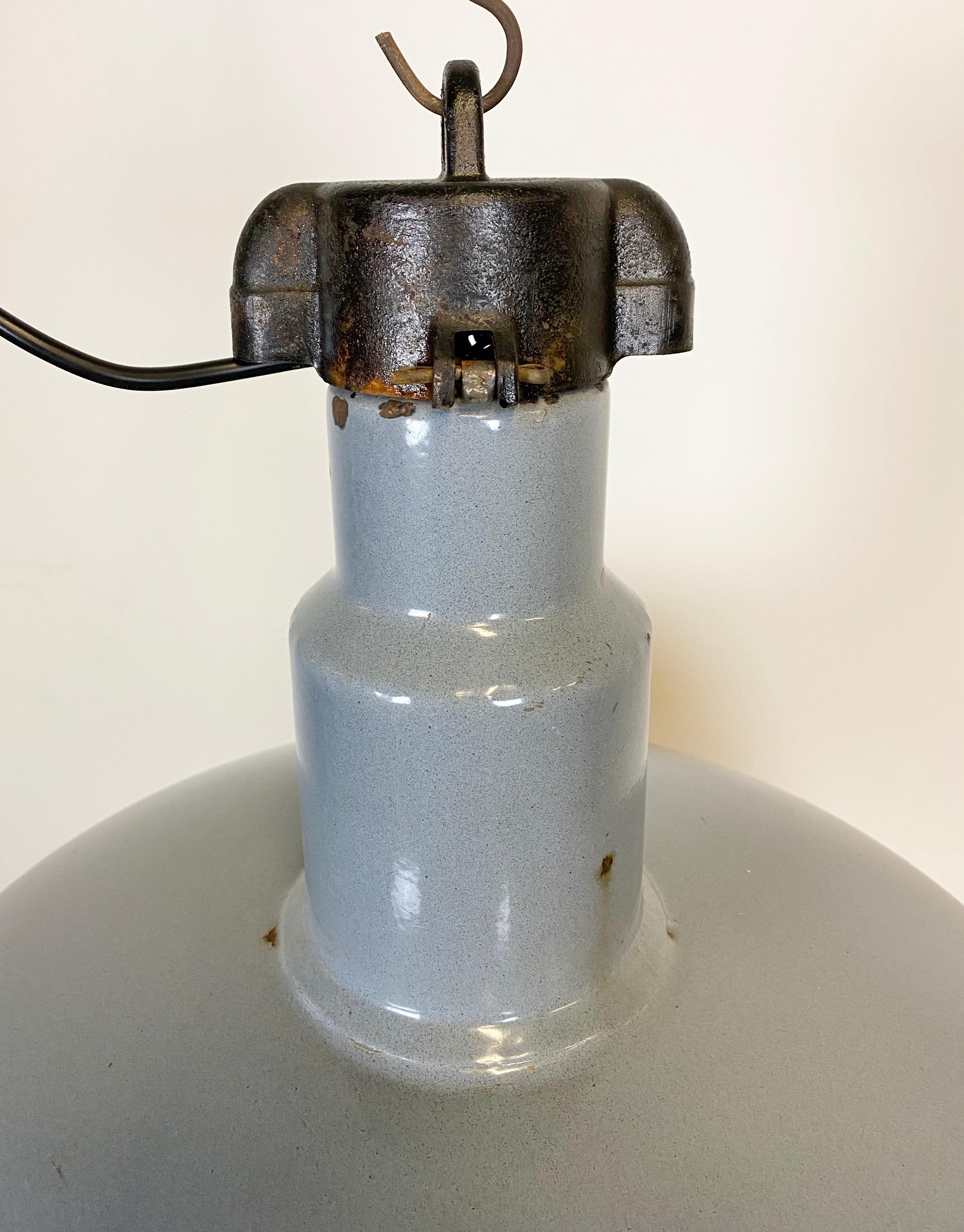 This Industrial lamp was made in former Czechoslovakia during the 1950s. It features a grey enamel shade with white enamel interior. Cast iron top. New porcelain socket requires E 27 lightbulbs. The weight of the lamp is 4 kg.