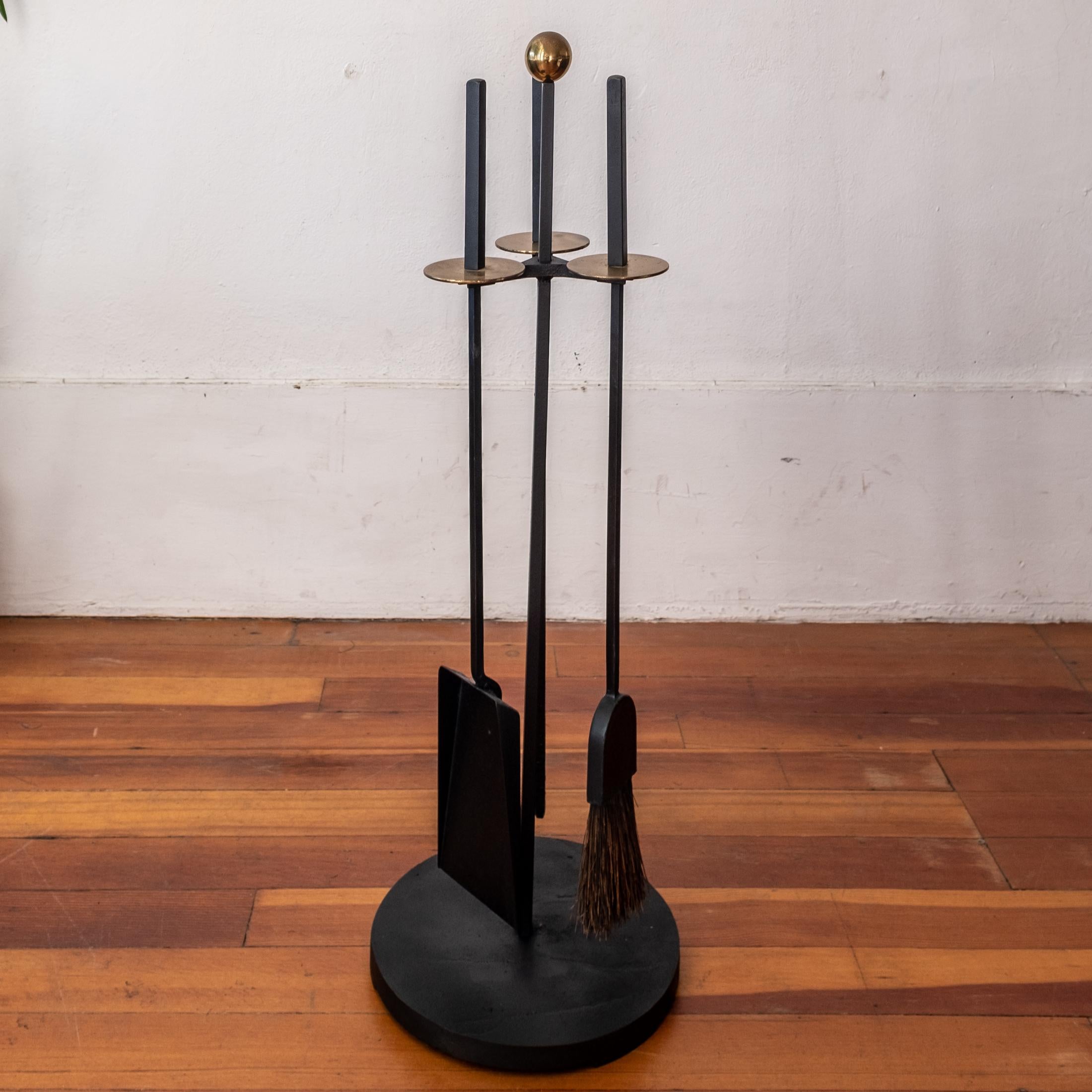 A set of modernist solid iron fireplace tools with solid brass discs and ball. The set includes a shovel, broom and poker. High quality and substantial construction with the original finish. 1950s

The set was designed by California Designer Mel