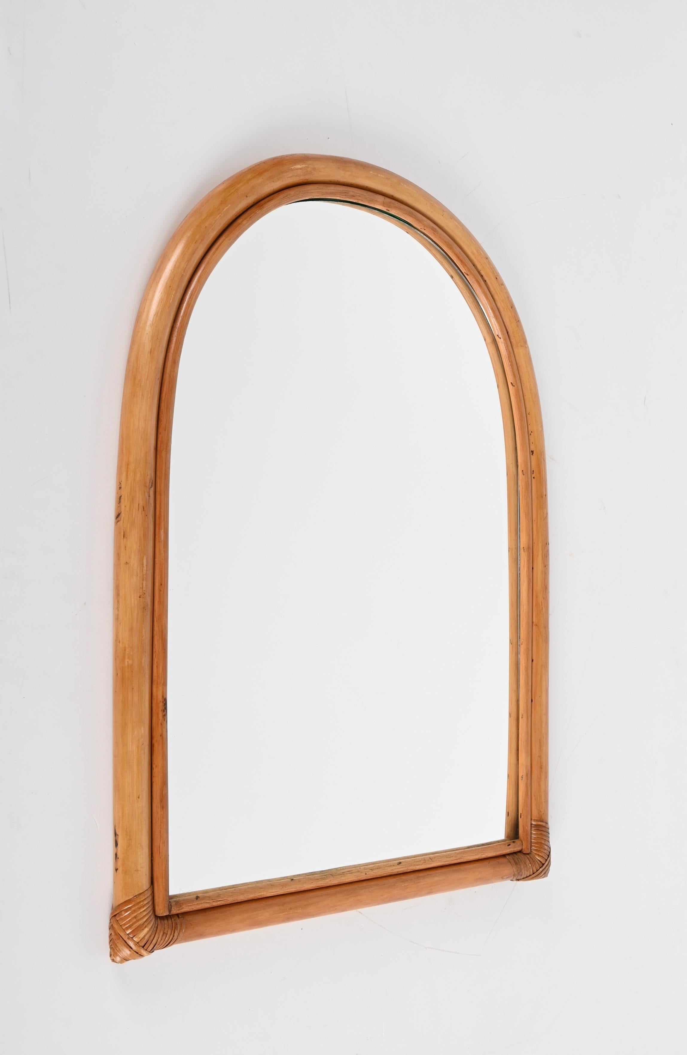 Wonderful midcentury arched-shaped mirror with double bamboo cane frame. This fantastic item was produced in Italy during the 1970s.

The way the two-round bamboo lines and the glass integrate via the arched wicker is superb and conveys infinite