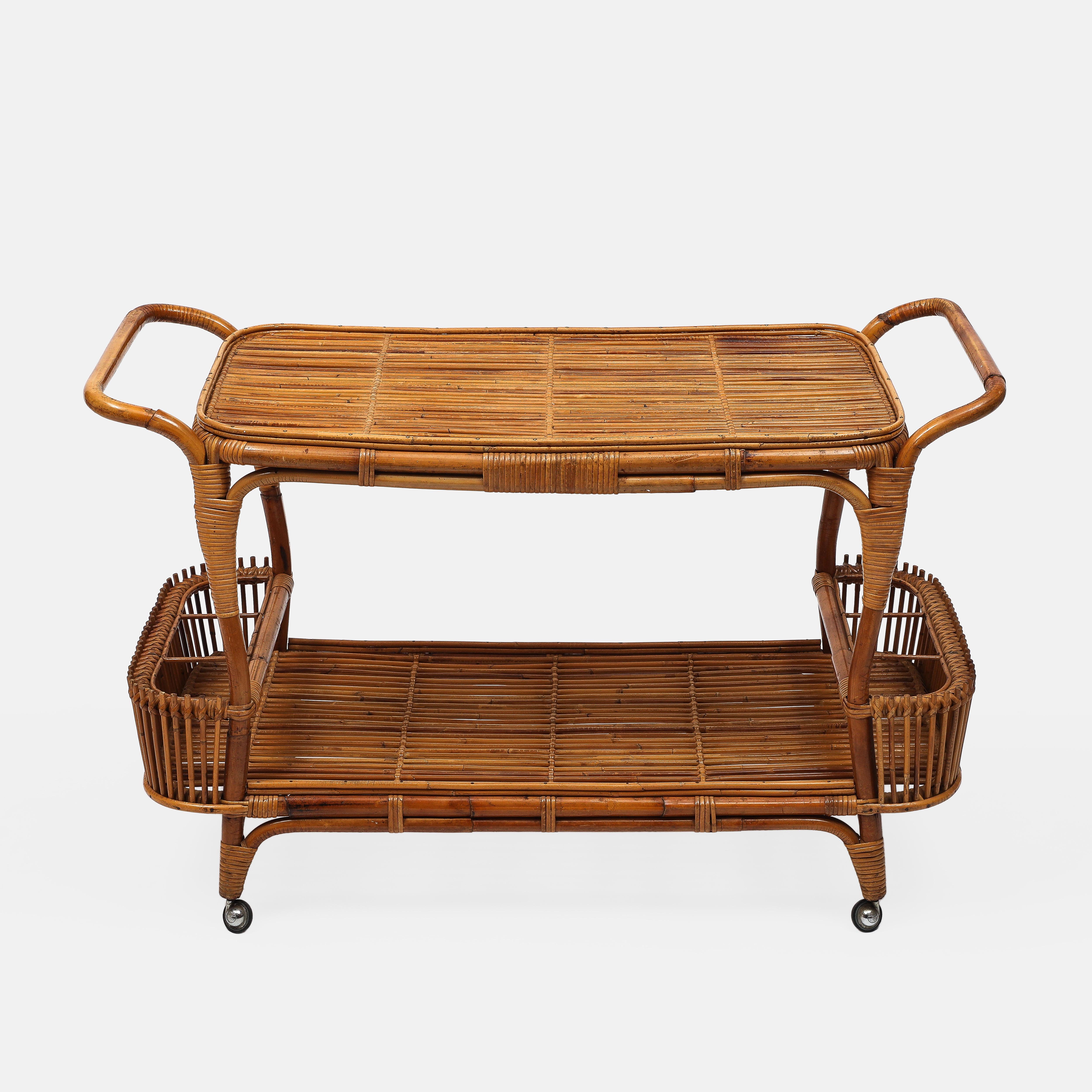 Carrito de bar orgánico italiano de dos niveles de bambú y ratán de mediados de siglo, al estilo de Bonacina, con dos asas a cada lado, cestas portabotellas curvadas o bolsillos a cada lado, y terminación en ruedas de latón, Italia, años 60.  Este