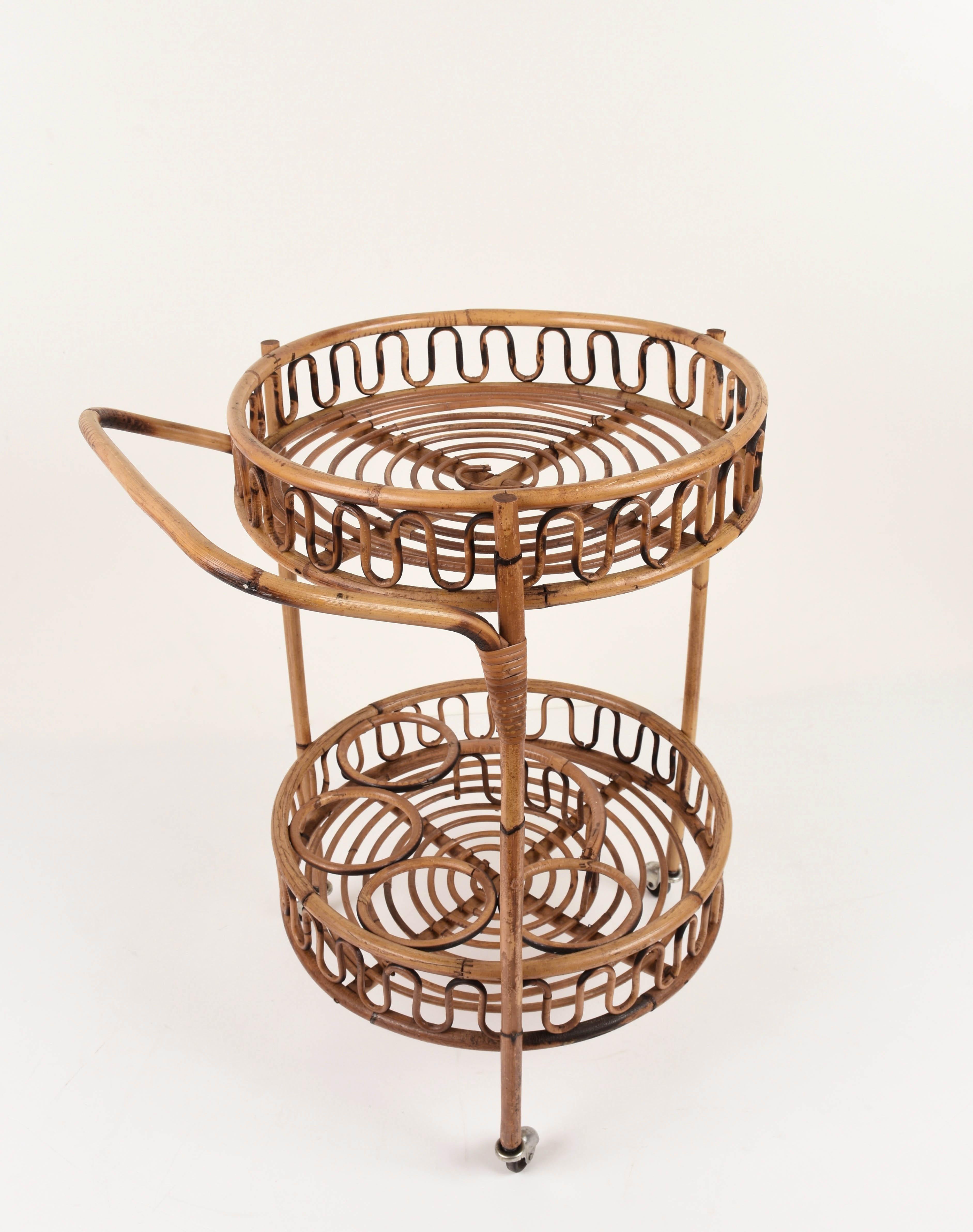 Fabulous midcentury Italian bamboo and rattan round serving bar cart side table. This fantastic piece was produced in Italy during 1960s.

This wonderful item has a bamboo structure and a rattan base with two levels and two large wheels at the