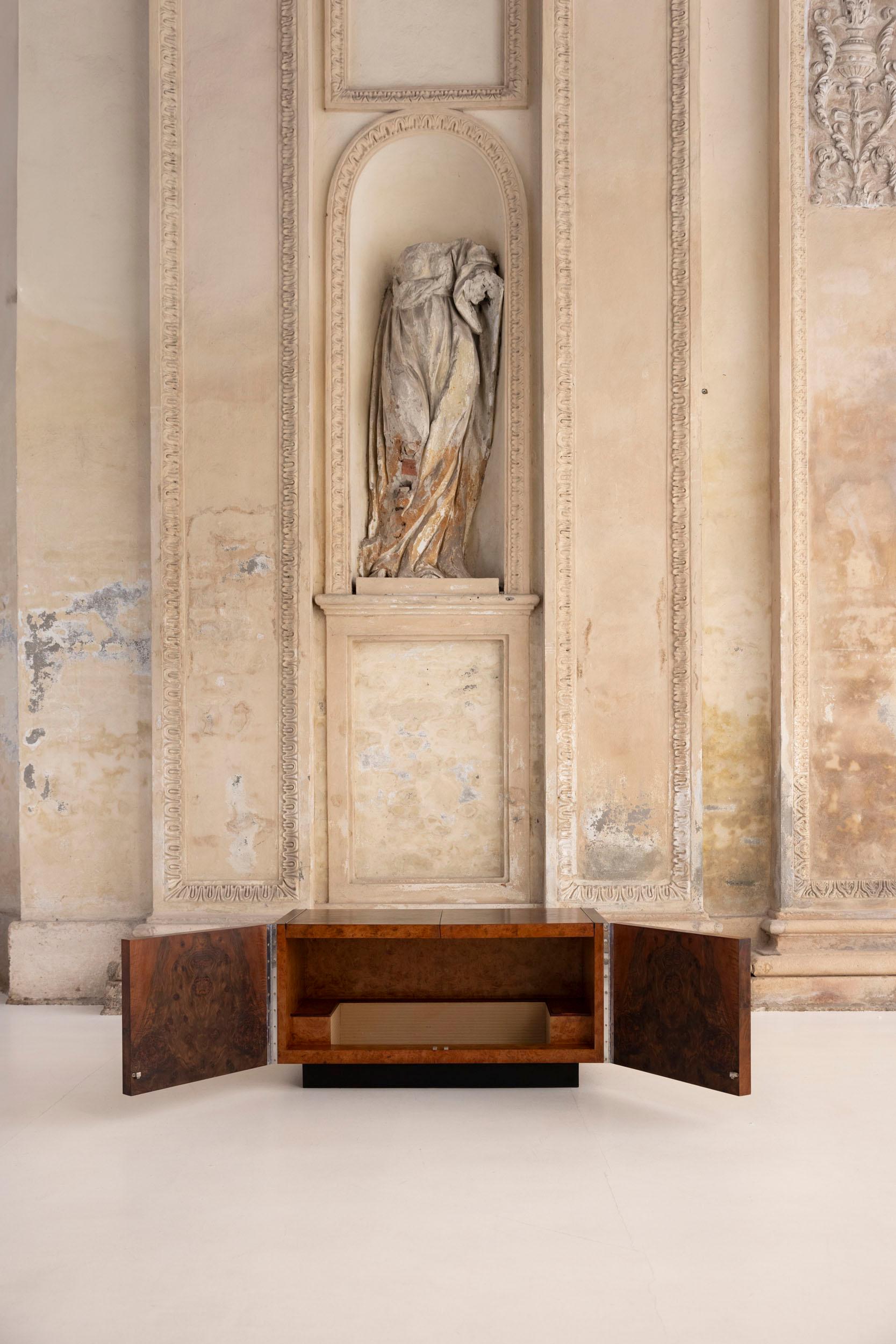 Este mueble bar de madera maciza de nogal de los años 30 es un bello ejemplo de artesanía vintage.
 El armario tiene dos puertas frontales, con una superficie superior formada por otros dos paneles abatibles. Cuando se abren, estos paneles descansan