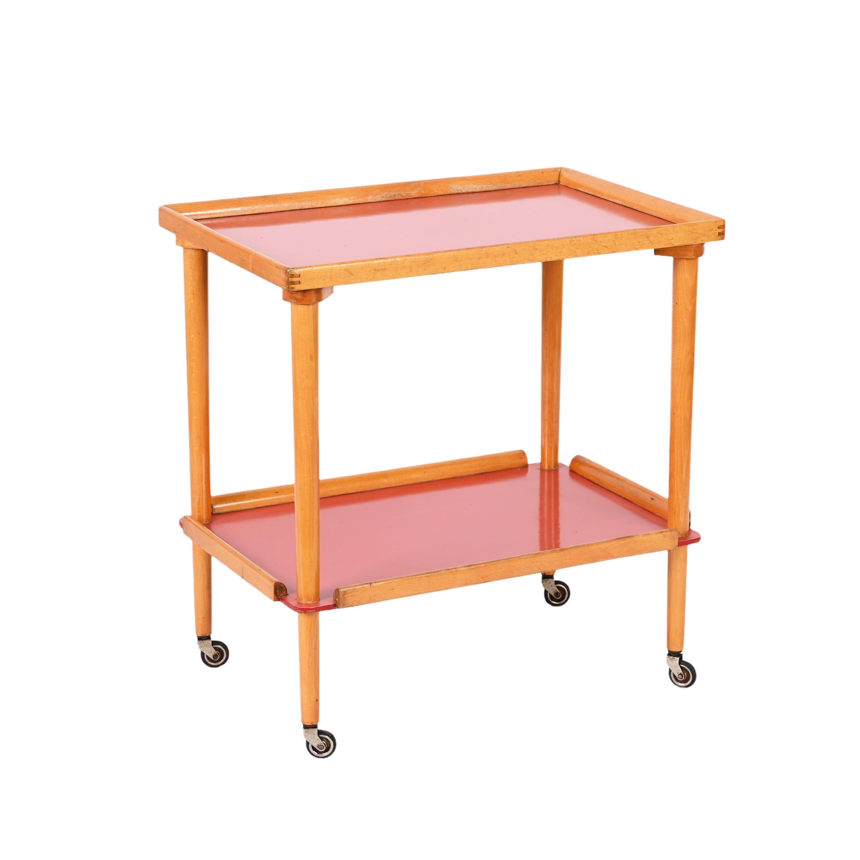 Fantastic midcentury serving trolley in beech wood with two formica red shelves. This unique piece was produced in Italy during the 1960s.

This is a wonderful item in fantastic vintage condition, very rare due to the two formica red shelves and