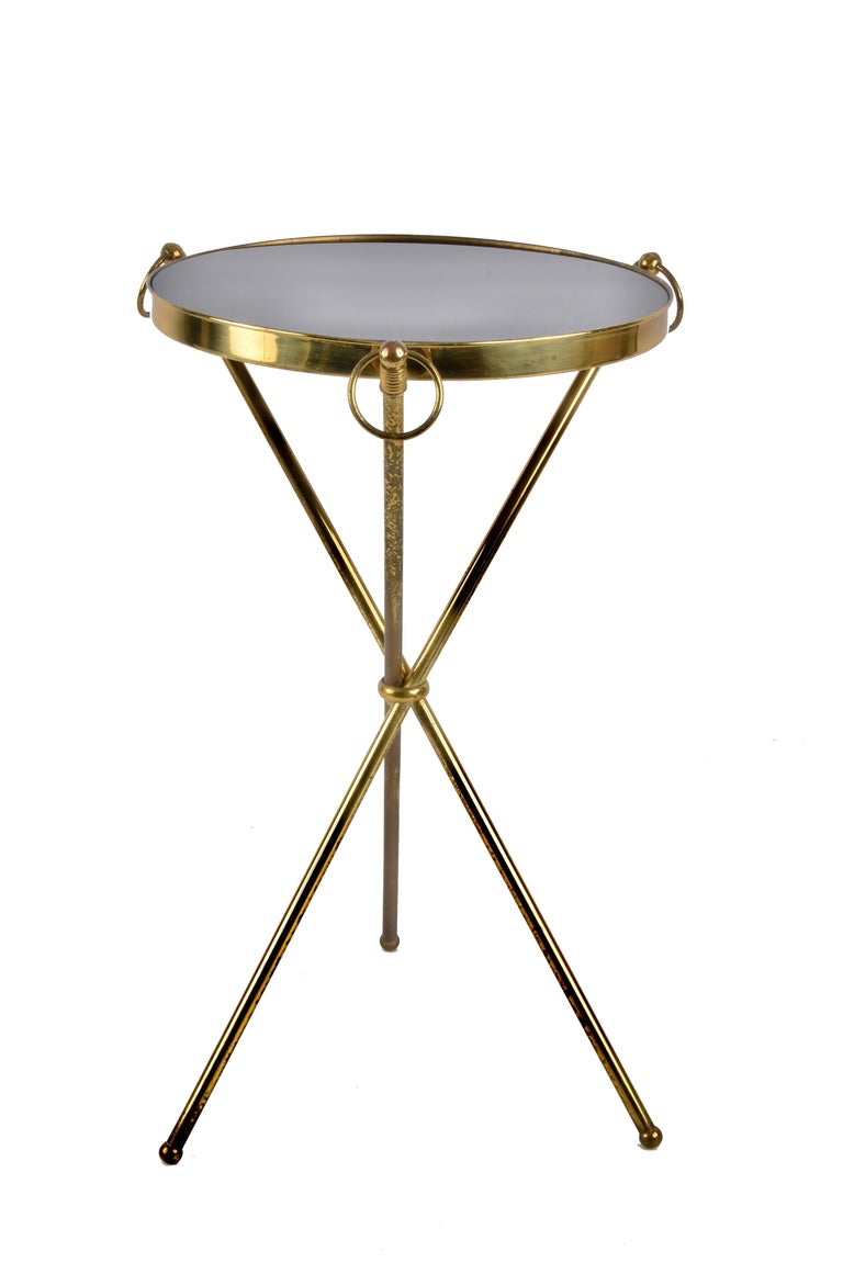 Amazing midcentury brass and glass round side table with tripod structure. This outstanding piece was designed in Italy during the 1950s.

The brass structure with three legs, combined with a black glass top is just breathtaking. Another iconic