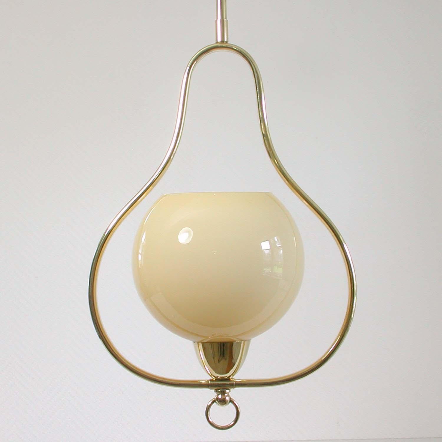 This elegant 1940s-1950s midcentury pendant was designed and manufactured in Italy.

The lamp is made of brass and has got a cream colored opaline lamp shade. The lamp has been rewired. This light can be used in every country of the world. It