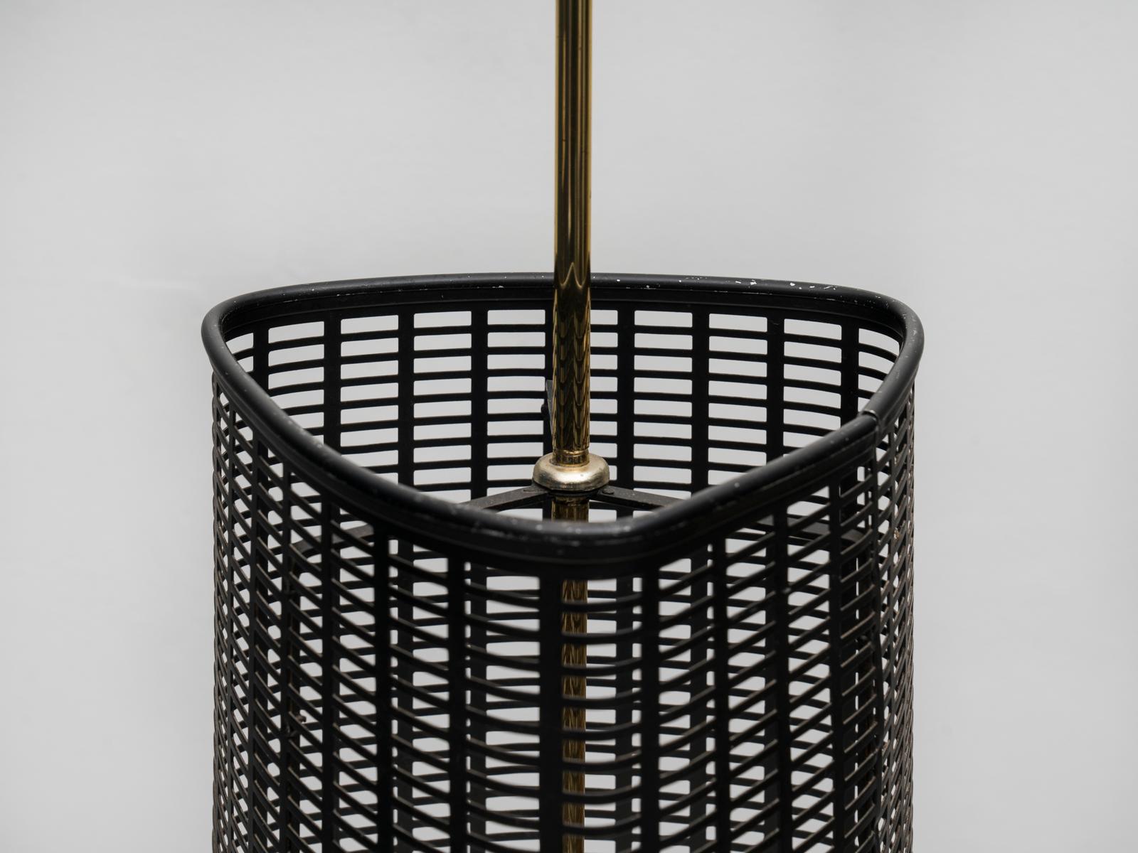 Elegant porte-parapluie italien des années 1950, de belle facture, avec une base en fonte, une tige en laiton avec un plateau verni ivoire et un corps en métal perforé noir. Peut-être inspirée par le travail de Mathieu Matégot, cette pièce est