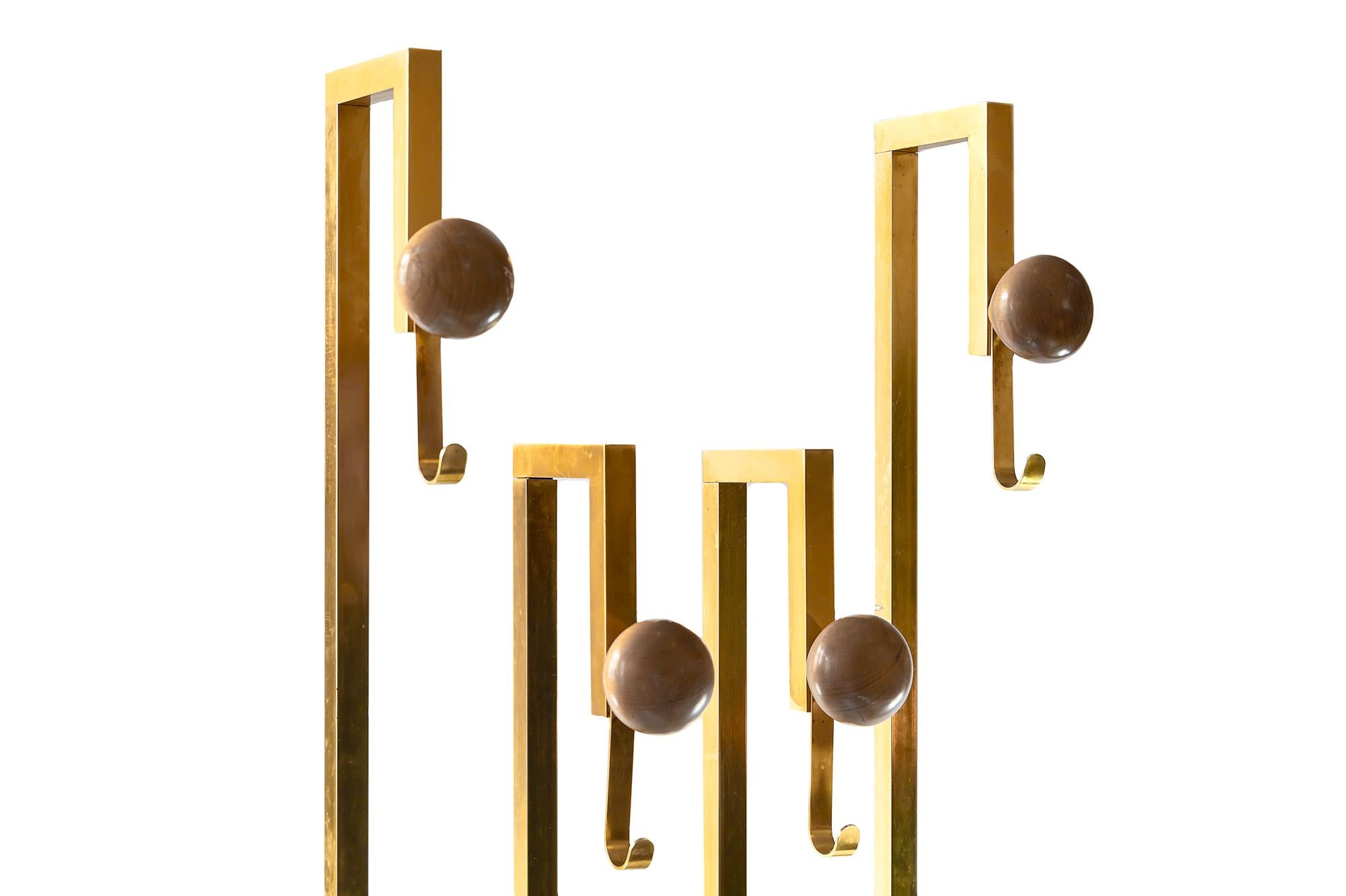 This midcentury Italian coat and umbrella rack is made of brass that is satin finished. It's base is wood chipboard coloured in black matte finish. The round details are of solid wood.