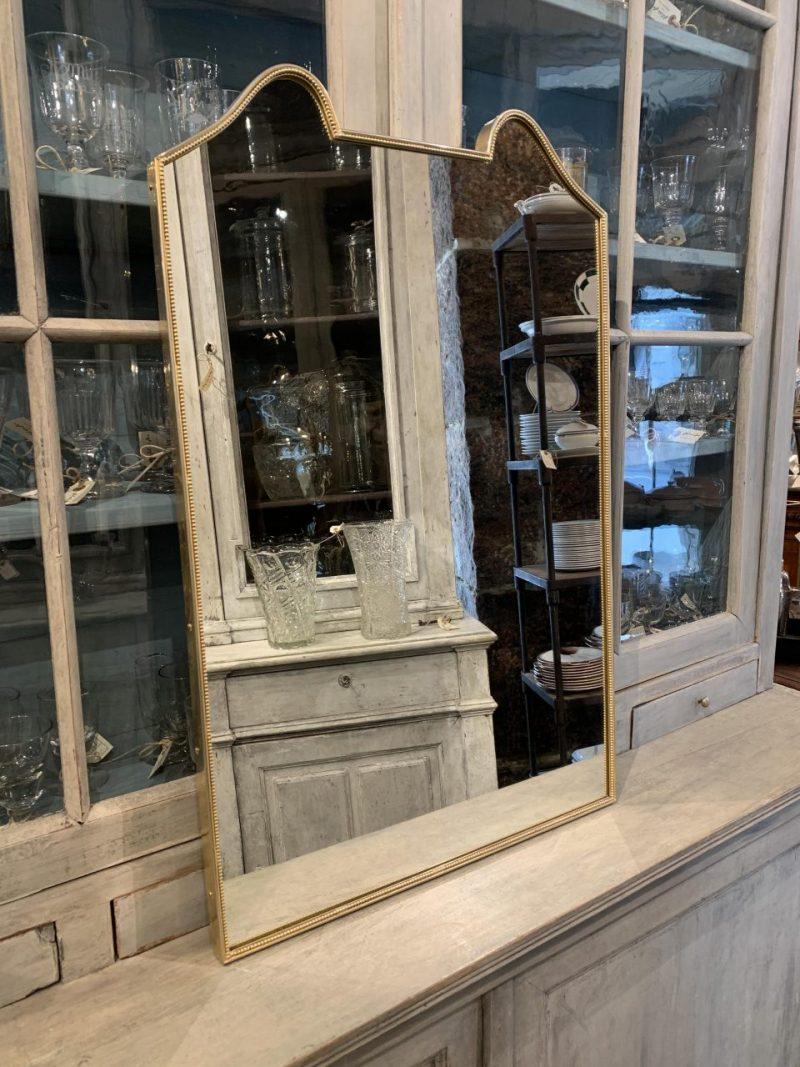 Beautiful midcentury Italian wall mirror, with a sleek brass frame in a stylish imaginative and eye catching design at the top.

Stylistically related to designer Giò Ponti’s brass mirrors and has suspension fittings mounted on the back.

Notice