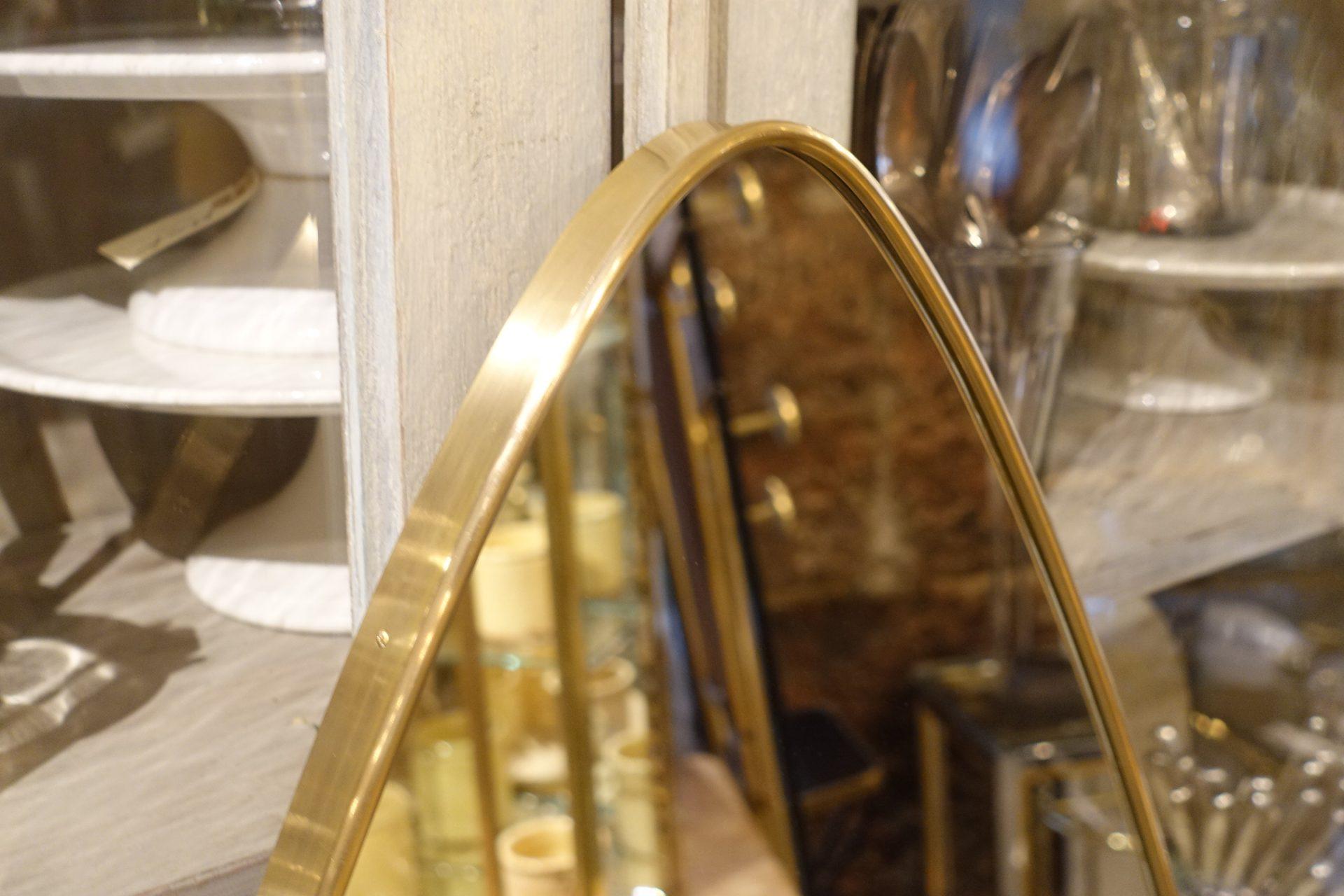 Handsome vintage oblong brass mirror from midcentury, Italy. Beautiful tapered oval shape with rounded ends. The mirror is stylistically similar to designer Giò Ponti’s mirrors and has mounting brackets behind. Notice the elegant and sleek brass