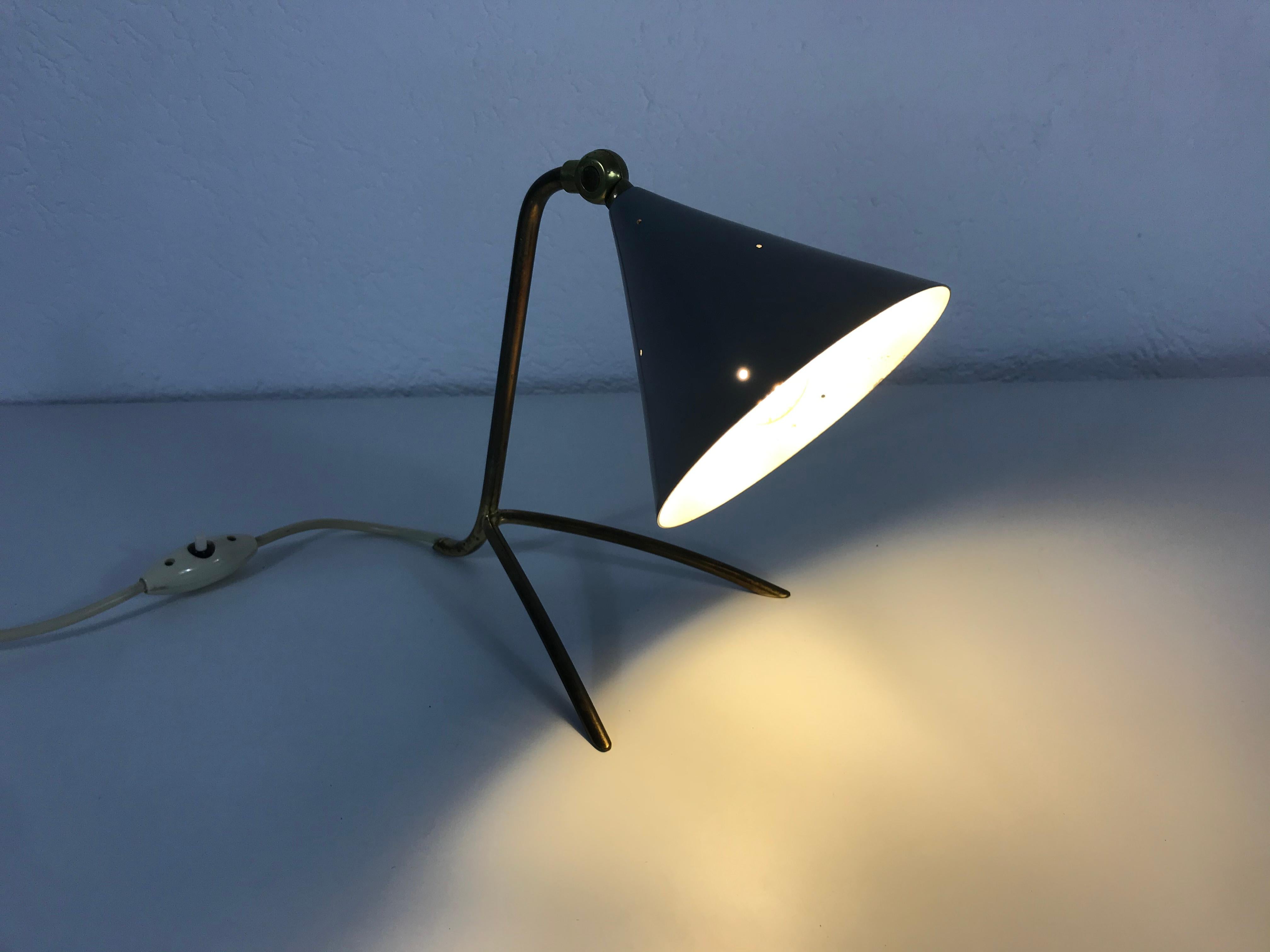 A beautiful table lamp made in the 1950s. It has a brass ball in the centre. The body and the three legs are made of brass. The lamp shade has a blue color and a shape of a cone. The table lamp has an beautiful Italian design.

The light requires