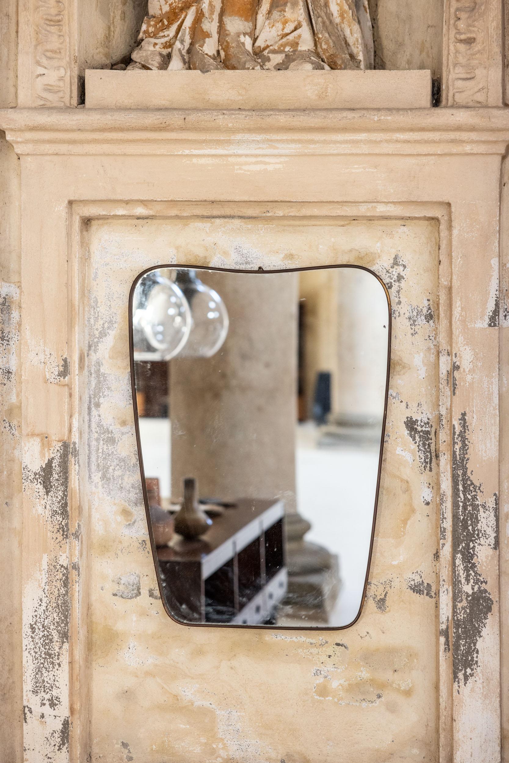 Grand miroir mural italien du milieu du siècle, attribué à Gio Ponti.
Elegant cadre en laiton doré de forme sinueuse, miroir en cristal d'origine et belle patine vintage. 
Parfait état vintage. 
Italie, années 1950