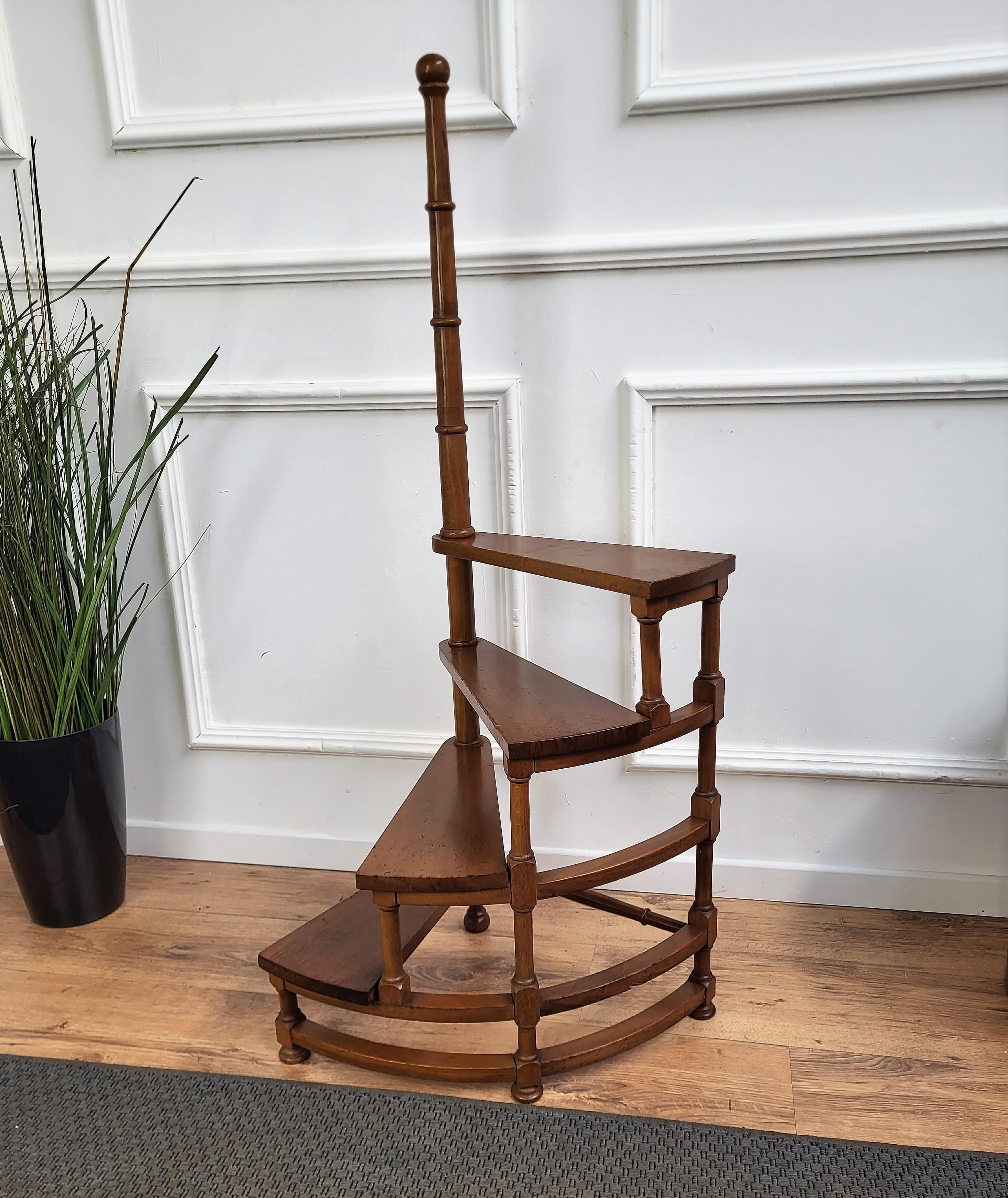Bel escabeau circulaire haut en bois de noyer sculpté en Italie, avec quatre marches enroulées autour d'un poteau central tourné, agrémenté d'un fleuron décoratif. Polyvalente et pratique, cette élégante bibliothèque essentielle est en excellent