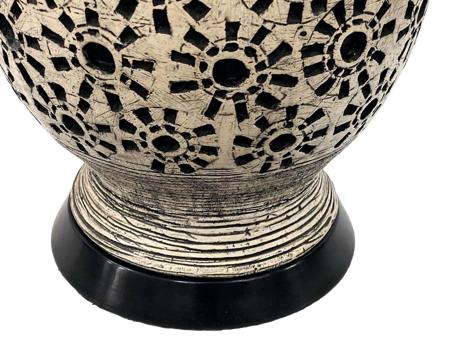 Eine italienische Tischlampe aus den 1960er Jahren mit stilisiertem Sonnenschliff-Motiv.

Abmessungen:
Höhe: 11