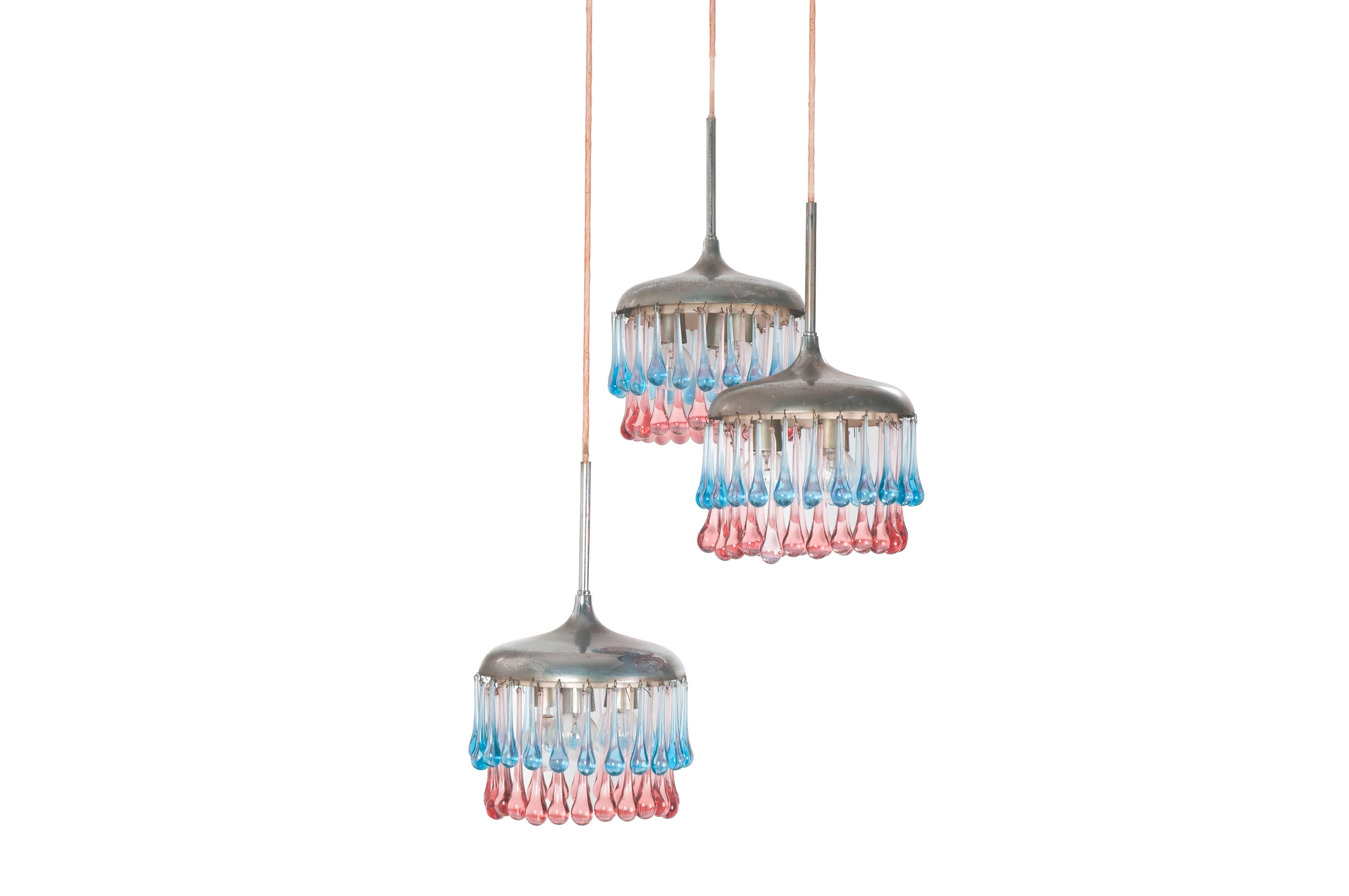 Una rara ed elegante lampada a sospensione prodotta da Stilnovo negli anni Cinquanta. Si tratta di 3 paralumi pendenti con decorazione a ciondolo di Murano. Ogni paralume presenta tre lampadine. L'altezza è indicativa e dipende dalla lunghezza del