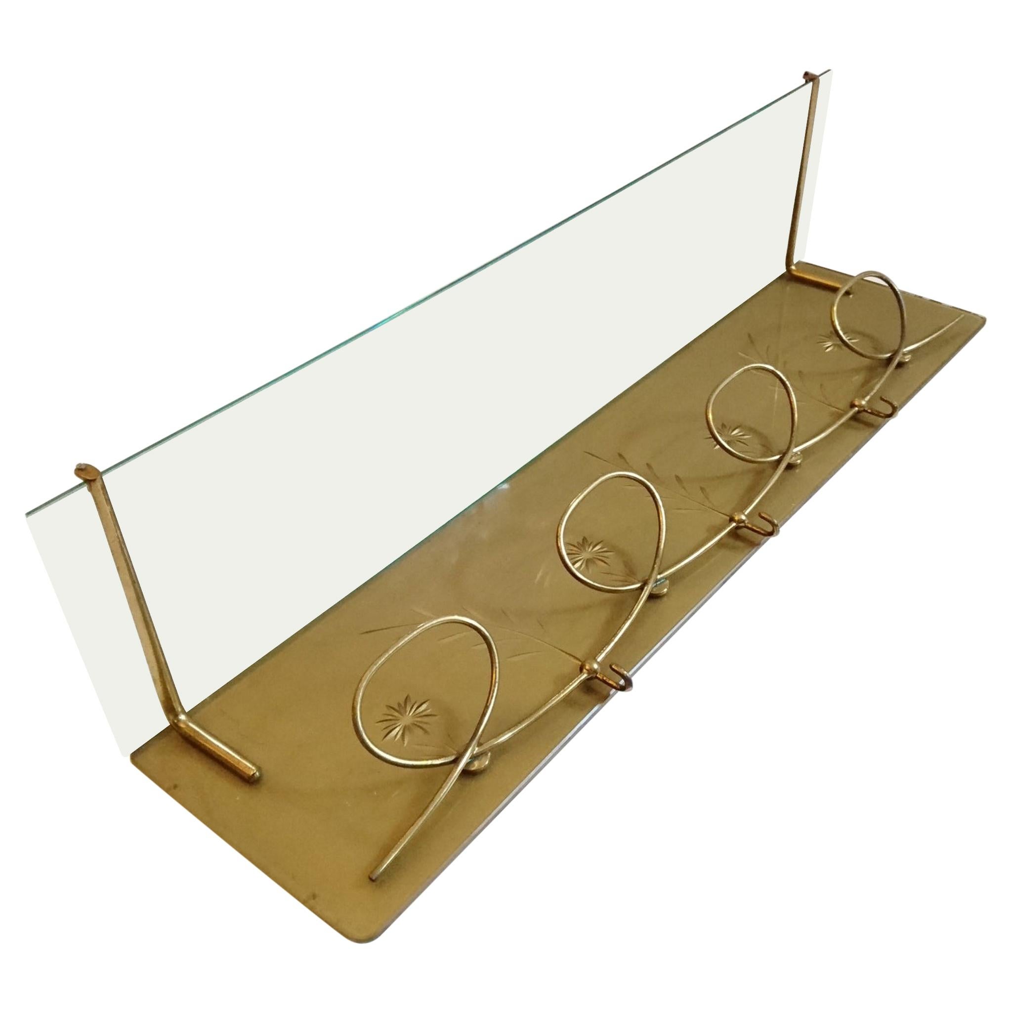 Elegant wall-mounted coat rack with a playful design in glass and brass and decorated with engraved flowers on gold base.