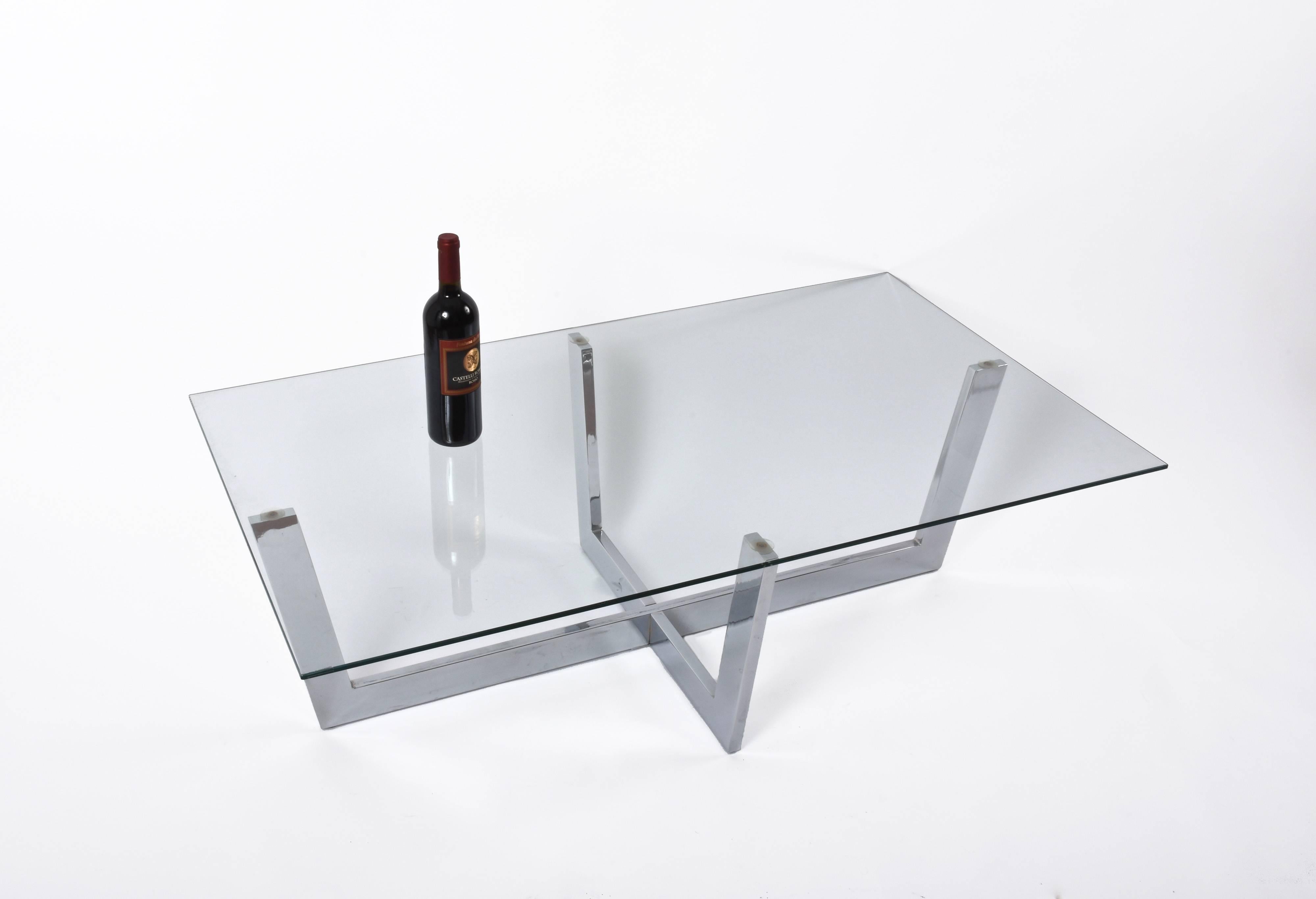 Wonderful rectangular coffee table in chromed steel with glass top produced in Italy during 1970s. 

This great midcentury piece, with a base made by two chromed steel pieces crossing in the center below the simple yet elegant crystal glass