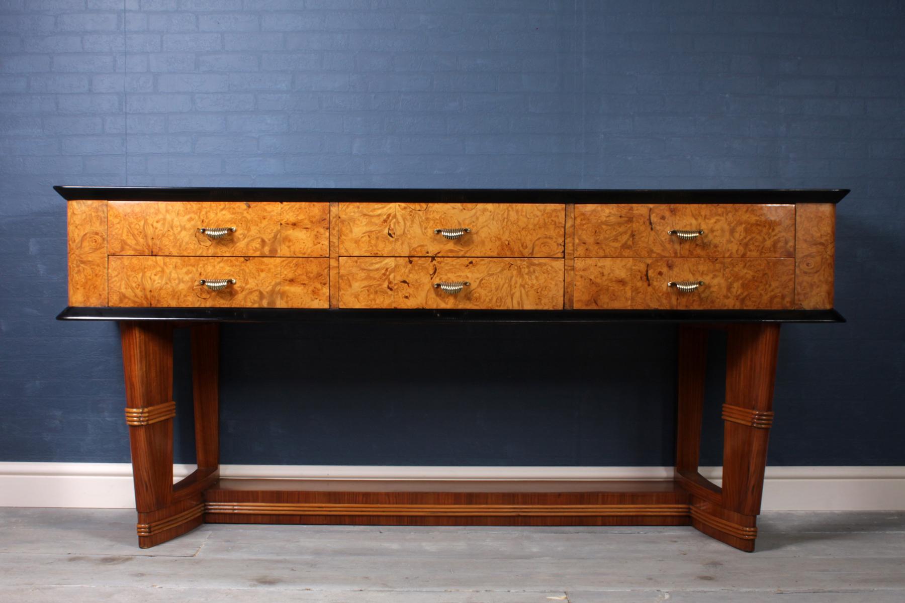 Midcentury Italian console table in burr maple.

A 1950s Italian six-drawer console table in burr maple and walnut with black glass top and brass handles the console has been professionally hand polished with a burnished luster finish, the console