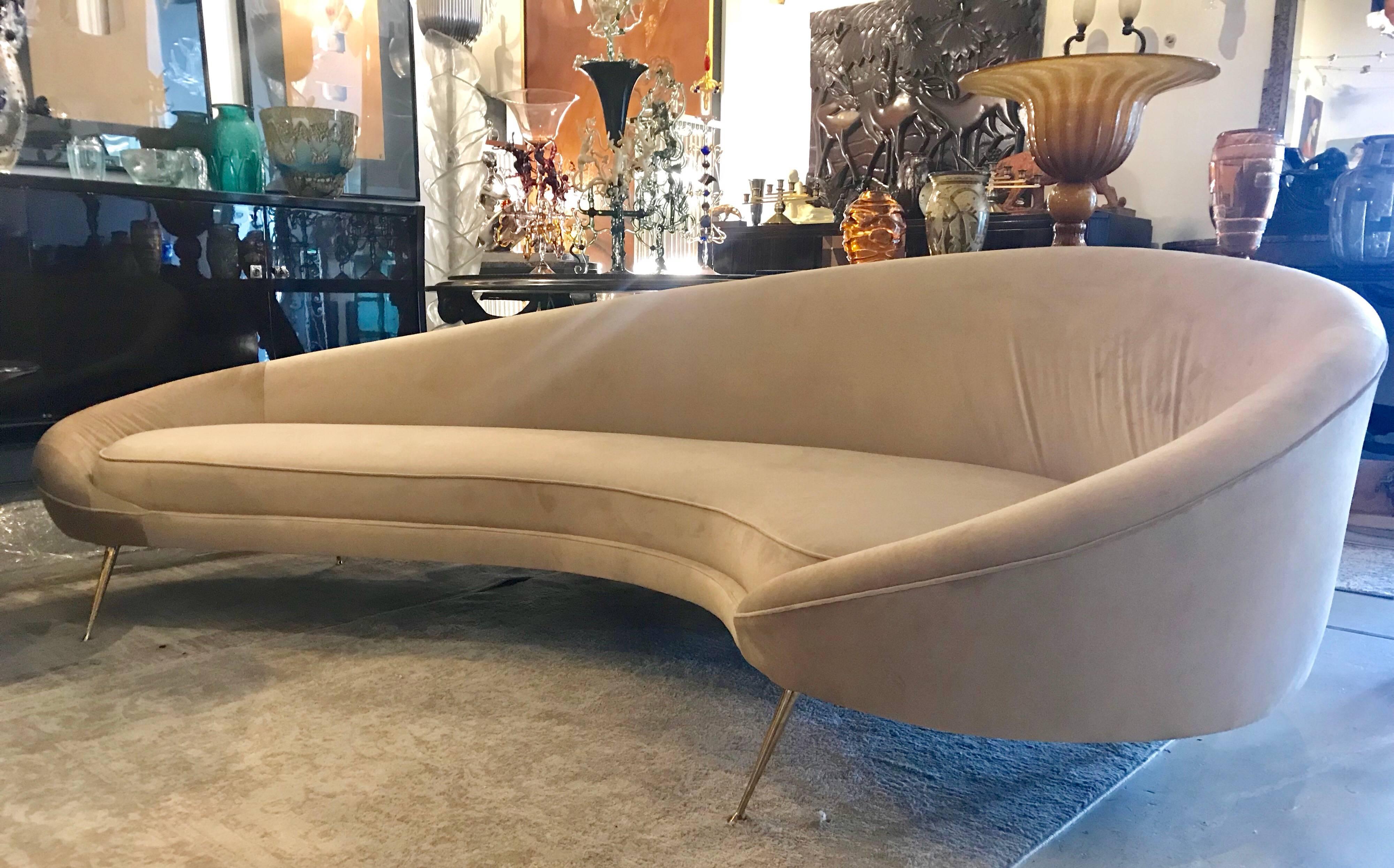 Large and comfortable midcentury Italian curved sofa with tapered brass legs and beige velvet upholstery. Beautiful from every angle.