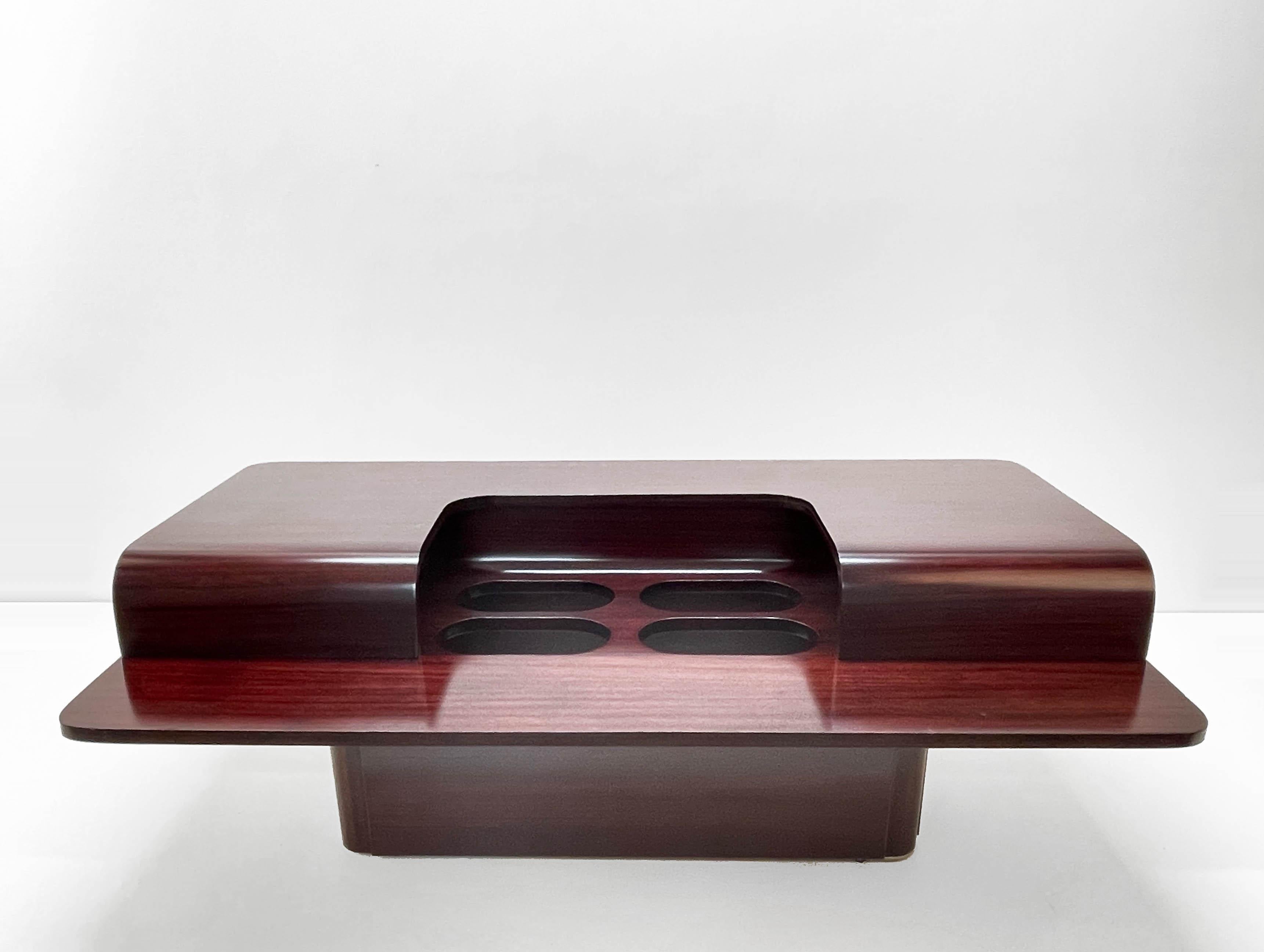 Amazing mid-century dark brown wooden coffee table with four bottle holders. This fantastic piece was designed in Italy during the 1970s.

This piece is wonderful because it seems it is made of one piece and great as it is made exclusively of dark
