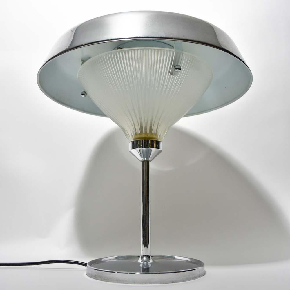 This is a beautiful Italian modernist lamp. It has a chromed steel structure and a chrome glass shade. The lamp serves both as an uplighter, creating a wonderful ambiance in a corner, and as down light that gives soft illumination at the table or on