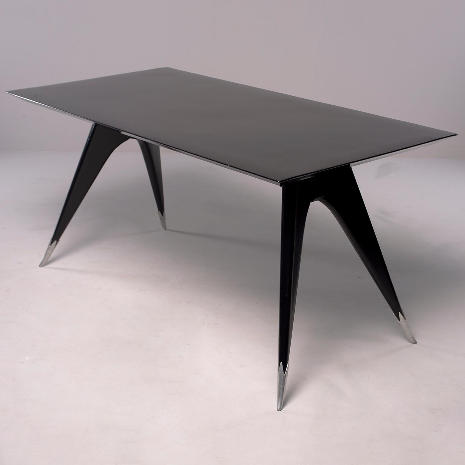 Circa 1960 Italian dining table has great mid century streamlined look with knife edge table top and tapered, splayed legs with silver foot caps.  New, professional ebonised finish. Found in Italy. Unknown maker. 