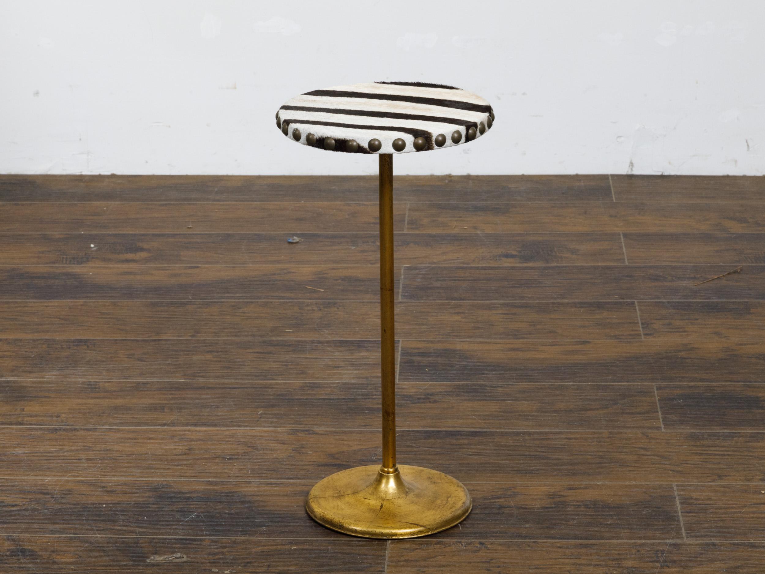 An Italian Midcentury gueridon side table from circa 1950 with circular zebra hide top and gilt brass pedestal base. This Italian Midcentury gueridon side table, circa 1950, is a striking fusion of exotic luxury and golden-era glamour. The circular