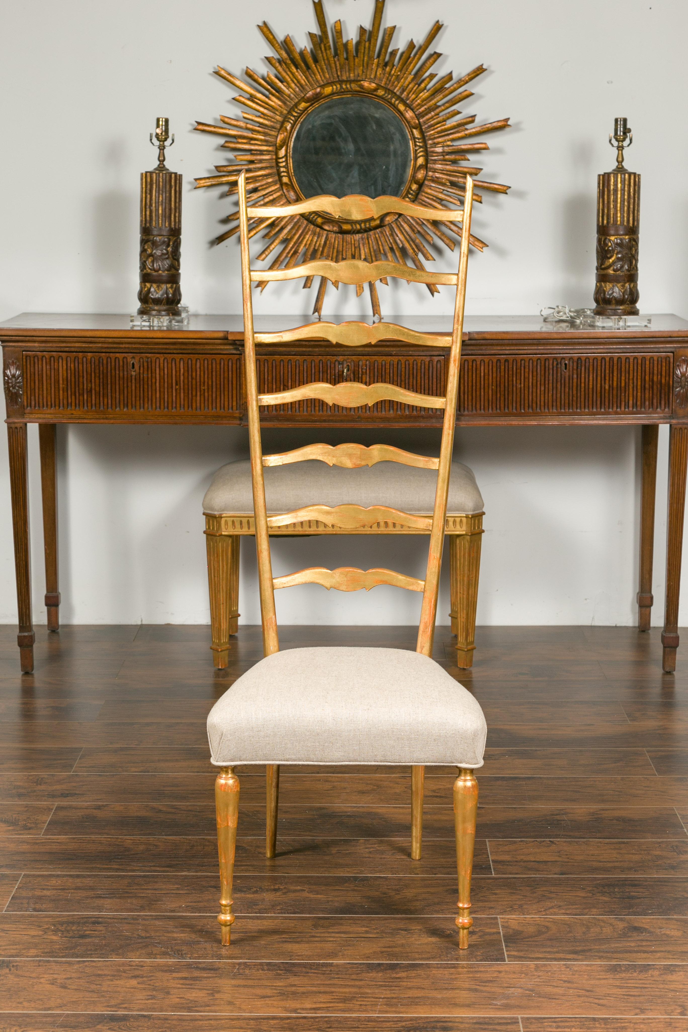 A vintage Italian giltwood high ladder back chair from the mid-20th century, with new upholstery and cylindrical legs. Born in Italy during the midcentury period, this giltwood chair features a high ladder back with scrolling accents, flowing