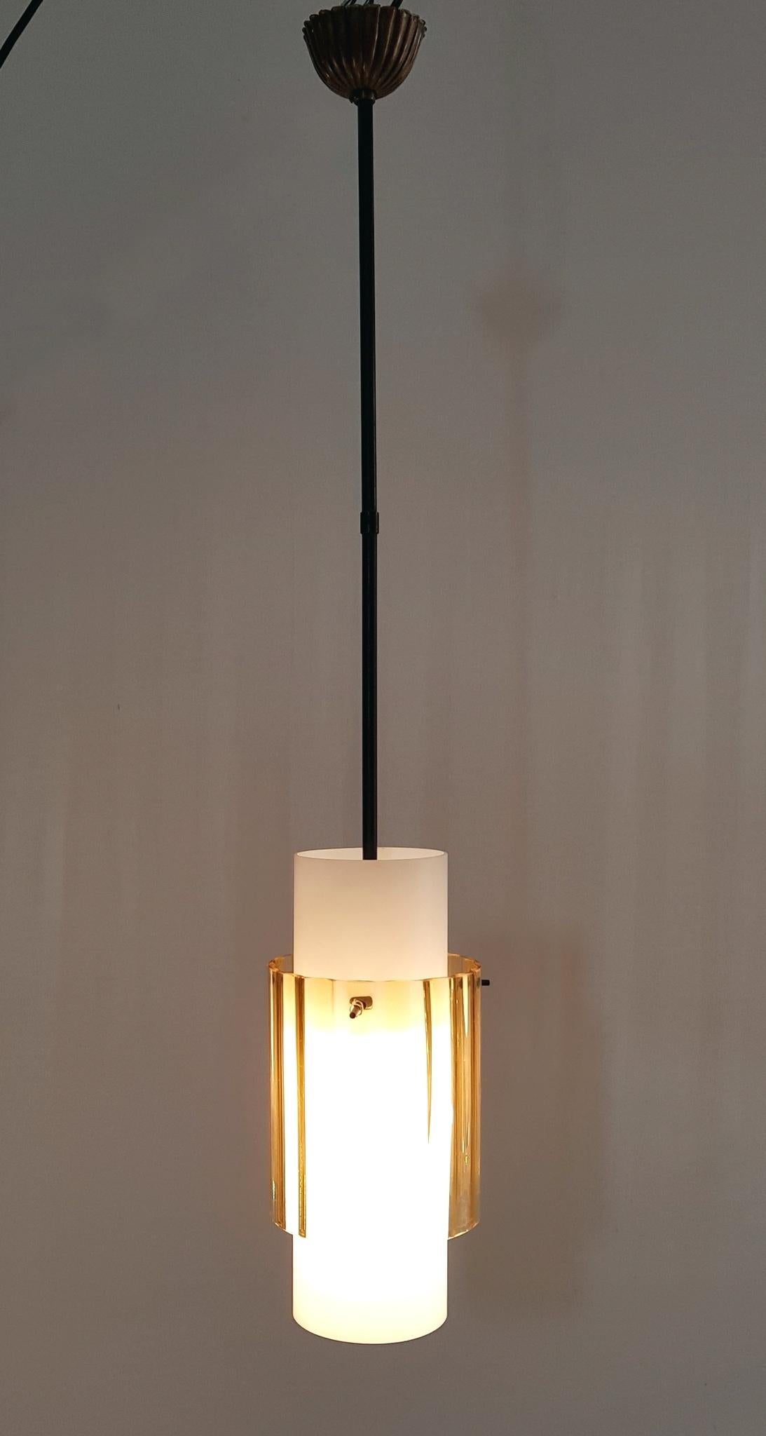 A pendant in with two cylindrical glass tubes. One is in opaline glass and the other one is in colored clear glass and sits on a black metal stem and finishes with a brass canopy. Gives a nice soft glow when lit. Very nice condition.