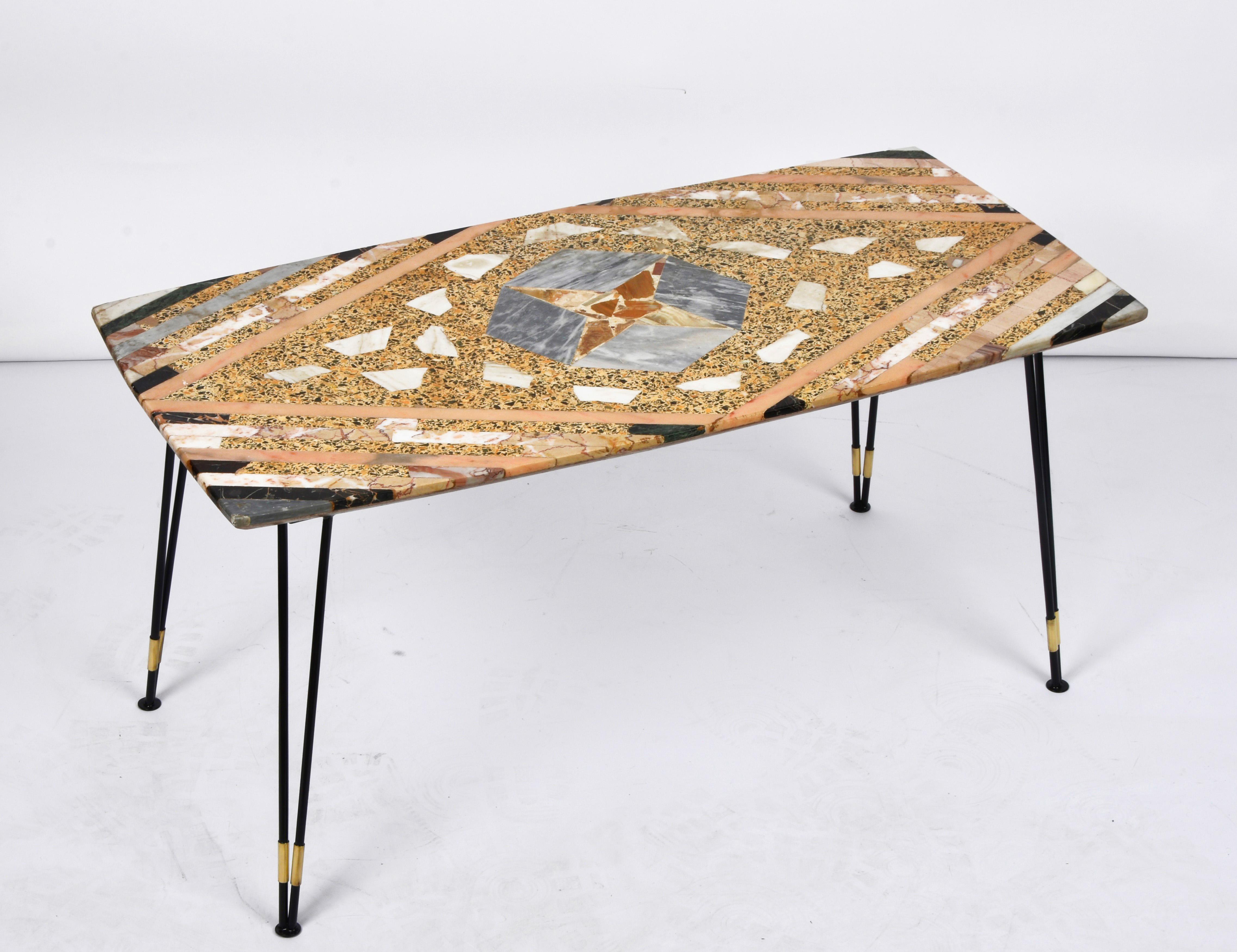 Incredible and unique midcentury inlaid marble coffee table with black metal lacquered base and stunning brass finishes. This amazing piece was produced in Italy during the 1950s.

This piece is unique because of the classic 1950s Italian design