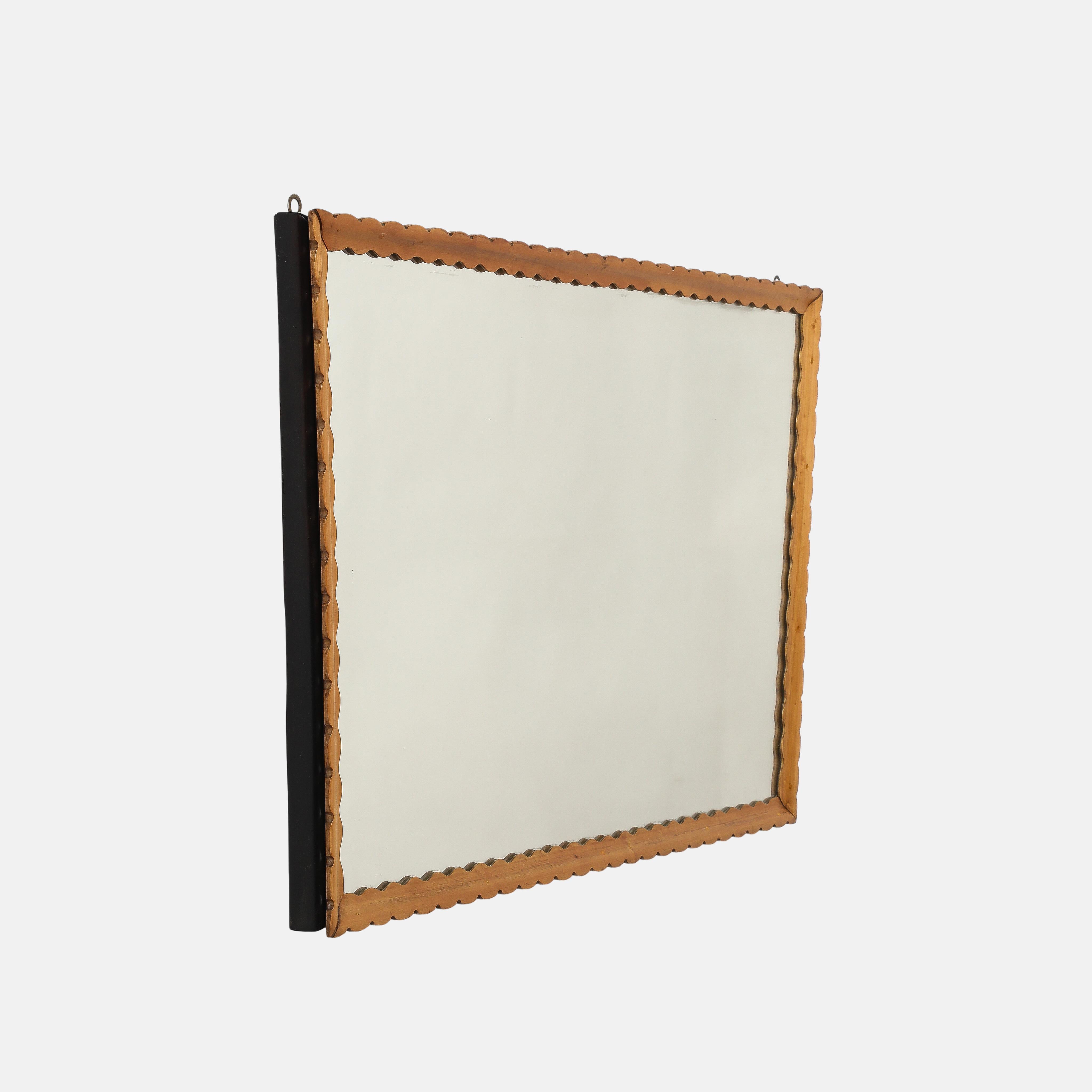 Elegante specchio da parete in legno smerlato intagliato orizzontalmente, con cornice in legno chiaro intagliata e smerlata o ondulata, con lati in legno scuro a forma trapazoidale, 1950. Questo delizioso specchio realizzato a mano è senza tempo e