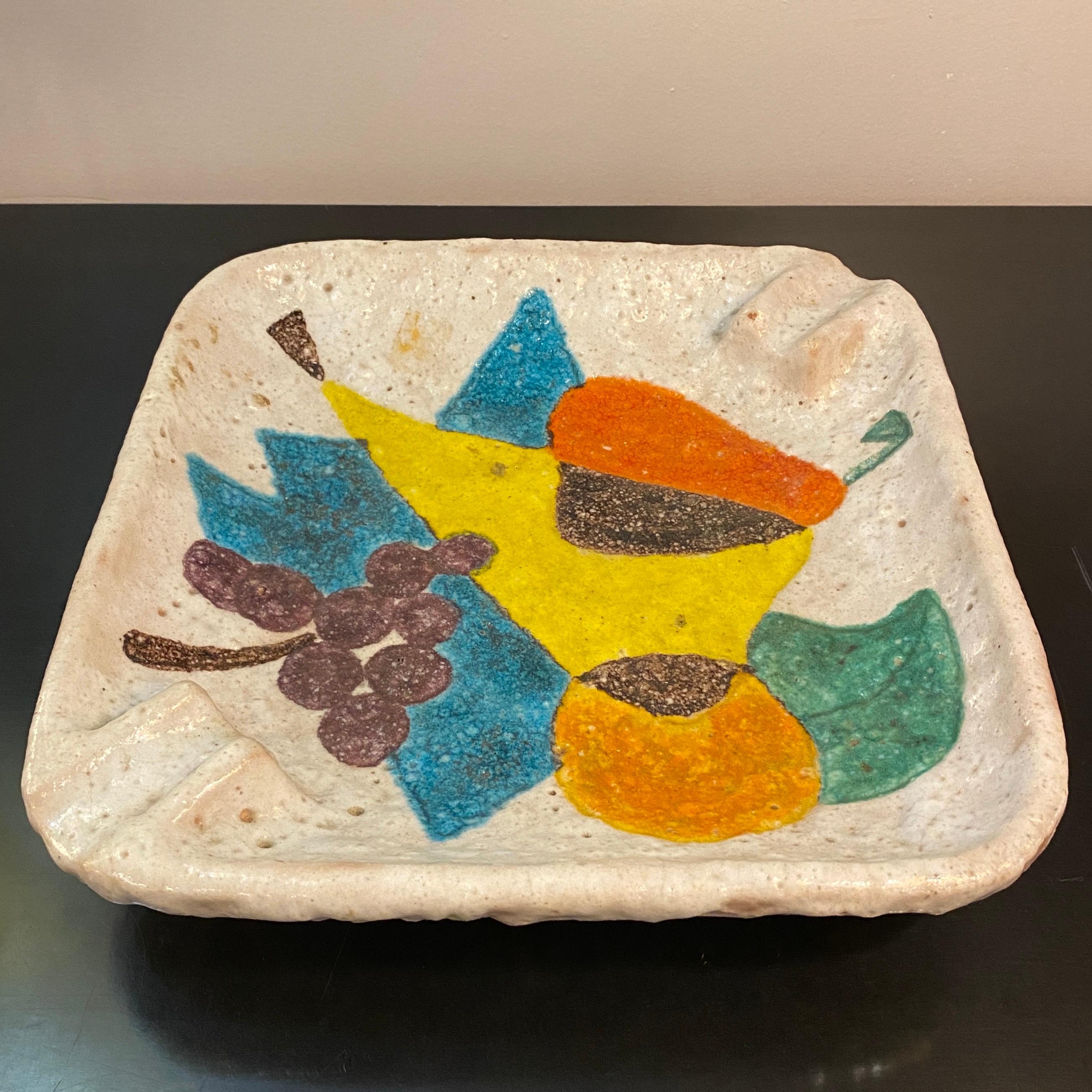 Large, Italian, midcentury modern, art pottery ashtray by Raymor features a painted, multicolor, abstract fruit arrangement.. The tray has a lava glaze technique which gives the surface a smooth yet irregular texture. The tray feels weighty with the