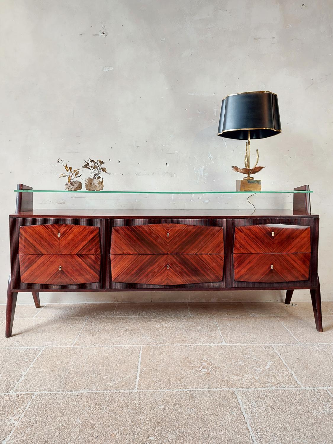 Sideboard by Osvaldo Borsani, Italy, 1950s. Beautiful design with ribbed laquered body and mahogany veneer on the sides, drawers and top in beautiful V pattern. With glass plate on top.

Borsani studied art and architecture in Milan. He became known
