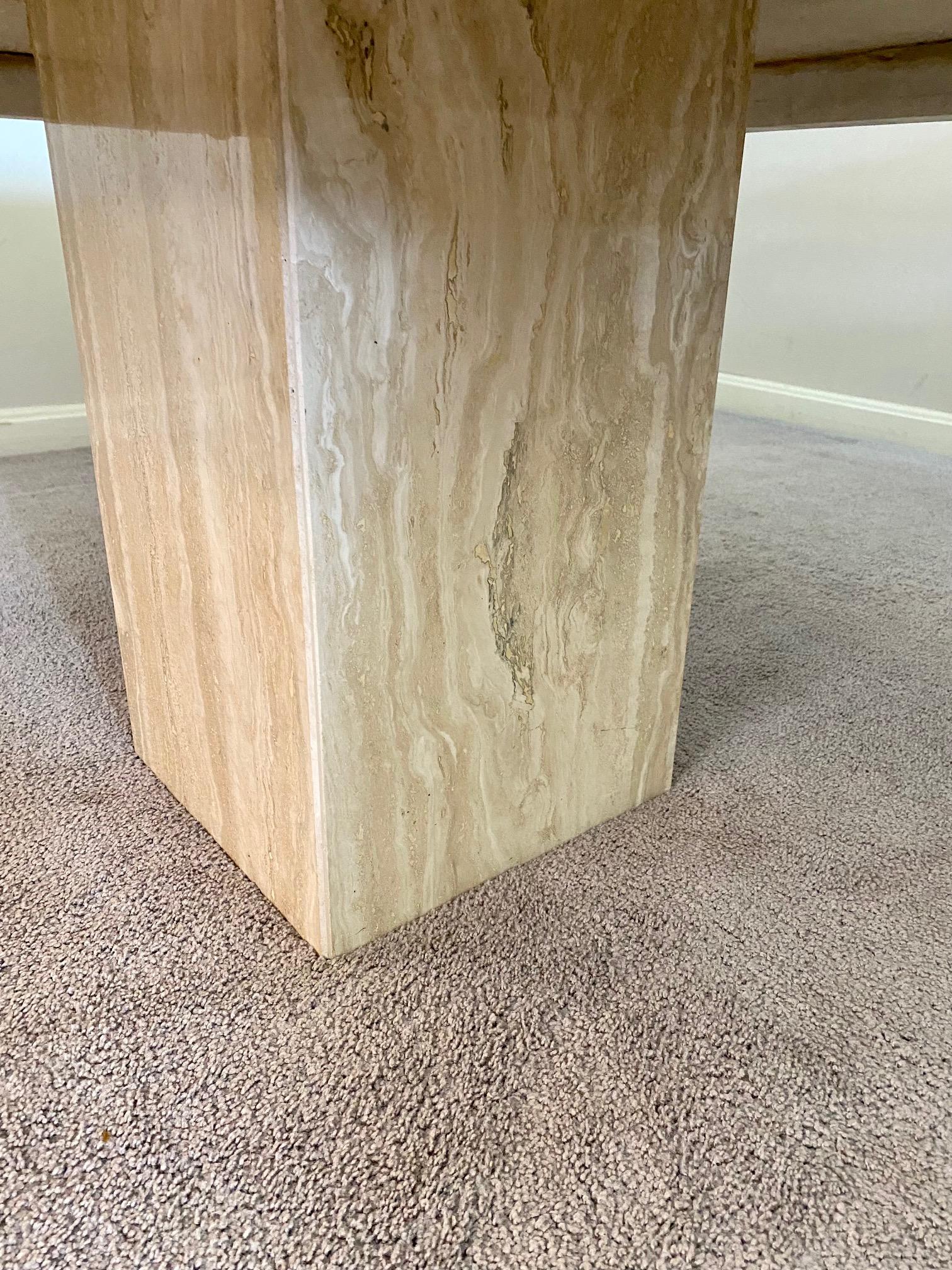 A lovely minimalist Italian modern travertine marble cocktail table circa 1970s-80s. This stunning square table top with beveled edge features shades of white and cream veining with beveled edges supporting a center square pedestal base. This piece