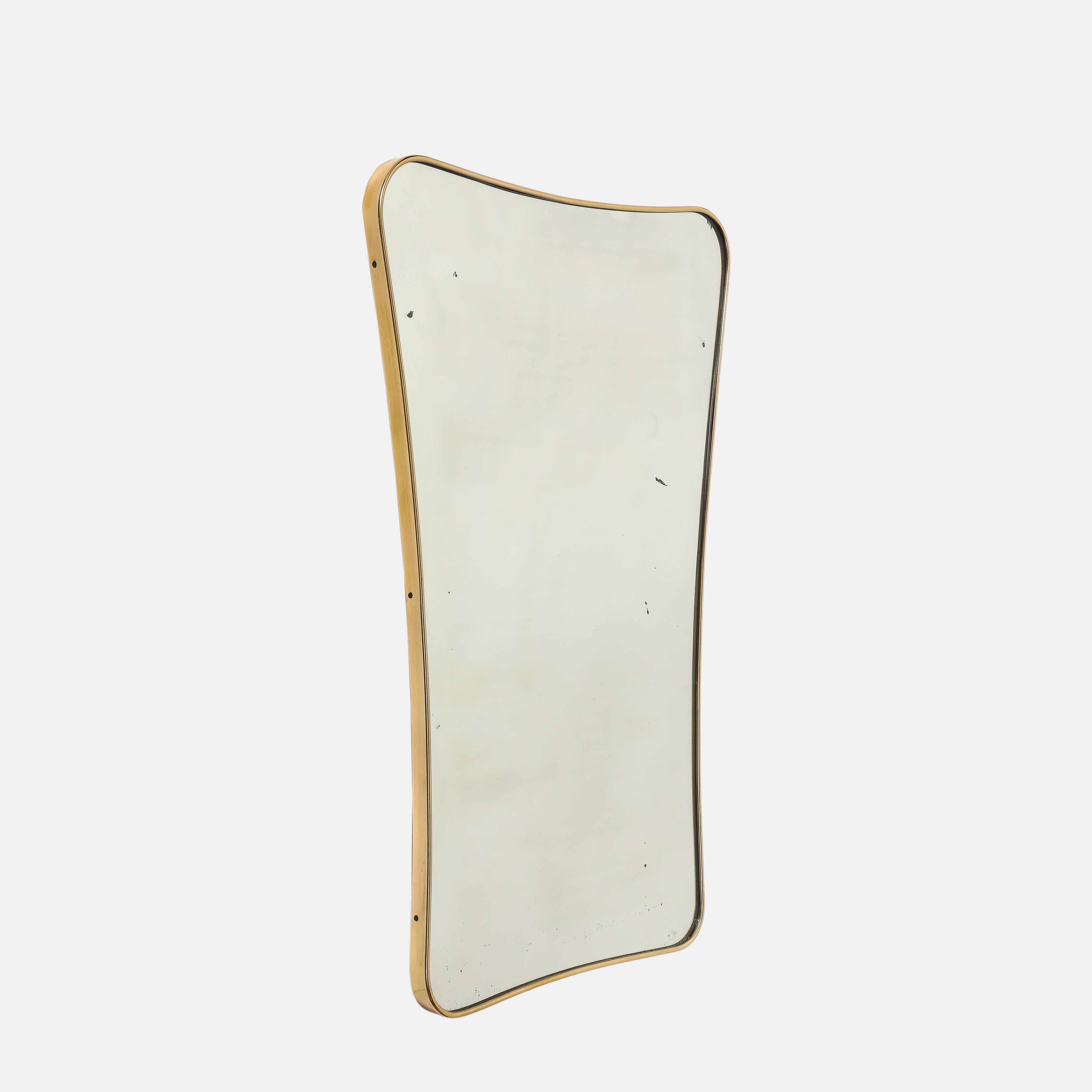 Grand miroir mural moderniste italien du milieu du siècle, composé d'un cadre en laiton façonné avec un sommet légèrement arqué et des coins arrondis qui s'effilent légèrement vers le bas, avec un support en bois partiel. Ce miroir original chic