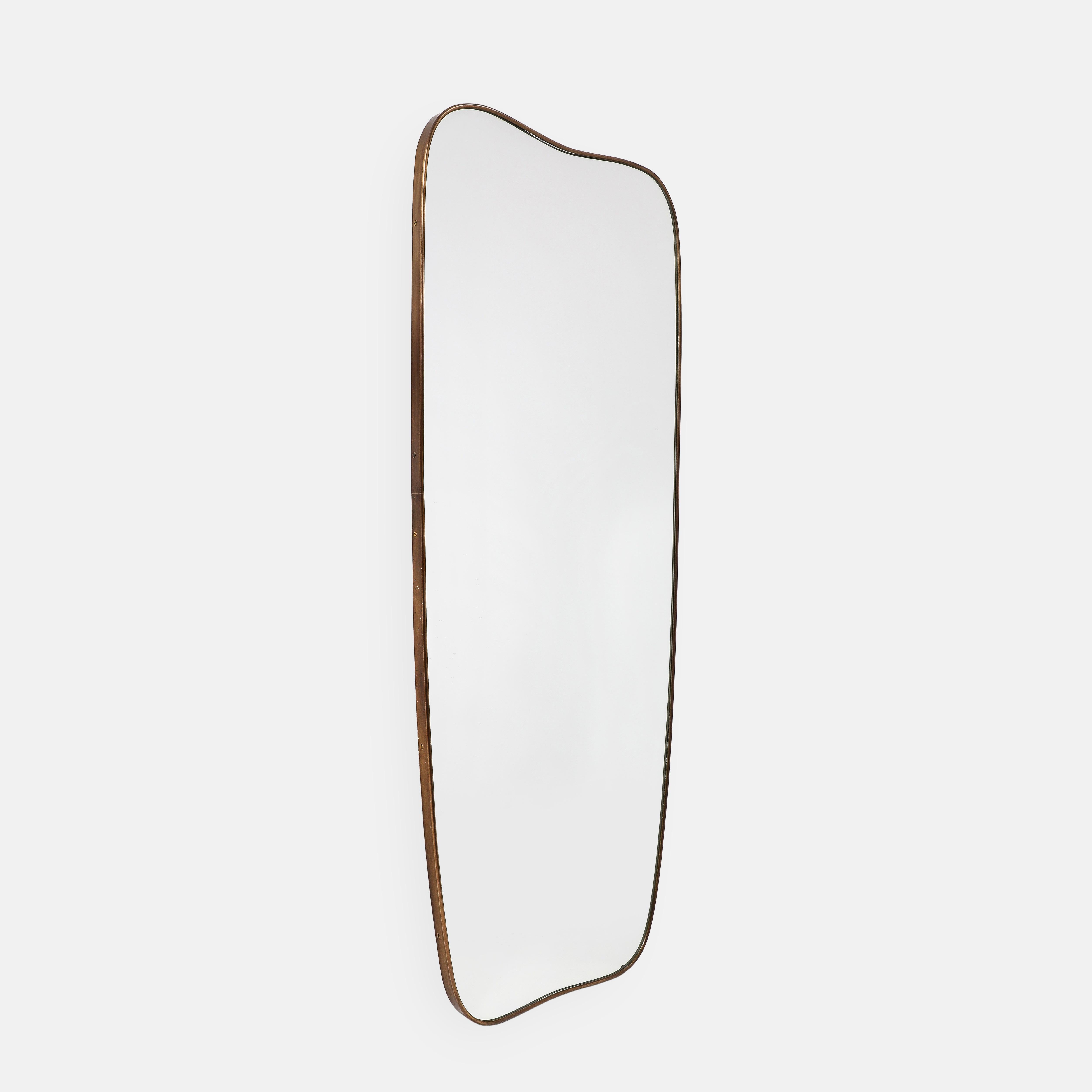 Specchio da parete modernista degli anni '50 composto da una cornice in ottone sagomata con parte superiore e inferiore delicatamente arcuata e angoli arrotondati che si assottigliano verso il fondo. Questo specchio chic è davvero un'icona del