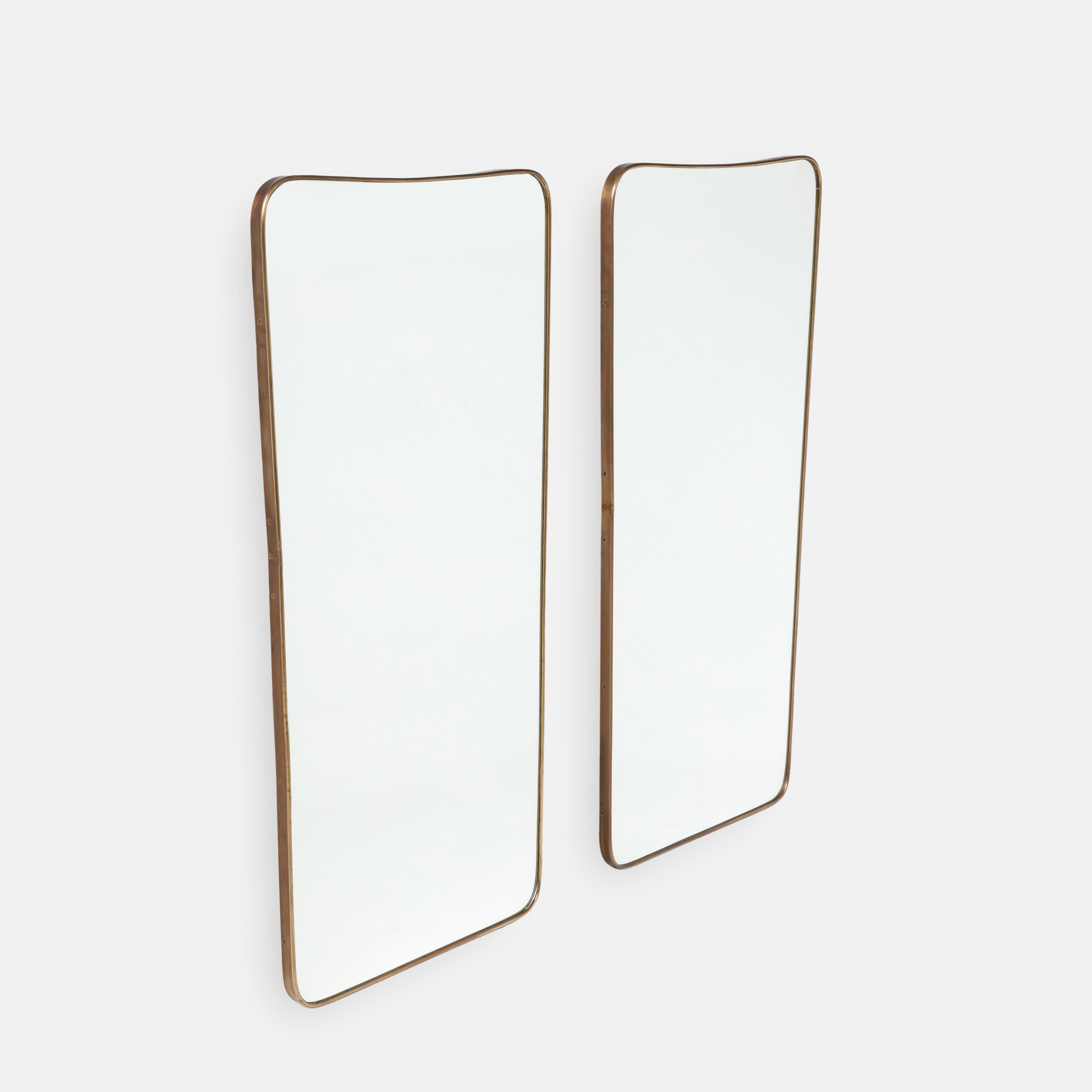 Paire de grands miroirs muraux modernistes italiens des années 1950, composés de cadres en laiton façonnés avec des parties supérieures légèrement arquées et des coins arrondis qui se rétrécissent vers les parties inférieures légèrement arquées.