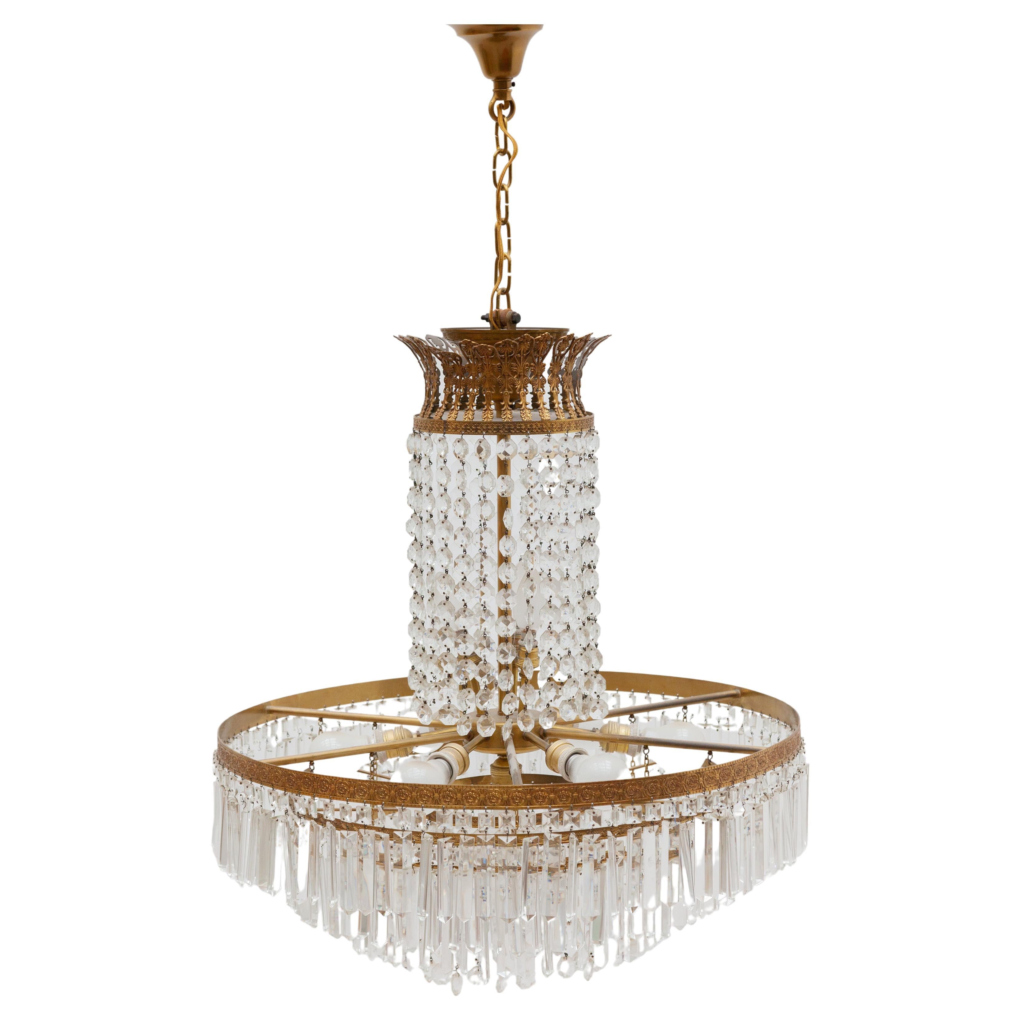 A crystal Victorian style waterfall chandelier with a brass frame in decorated flower pattern with hanging elongated in crystal faceted Murano glasses and diamant faceted round glasses. When the chandelier is lit with the seven bulbs of E27, a