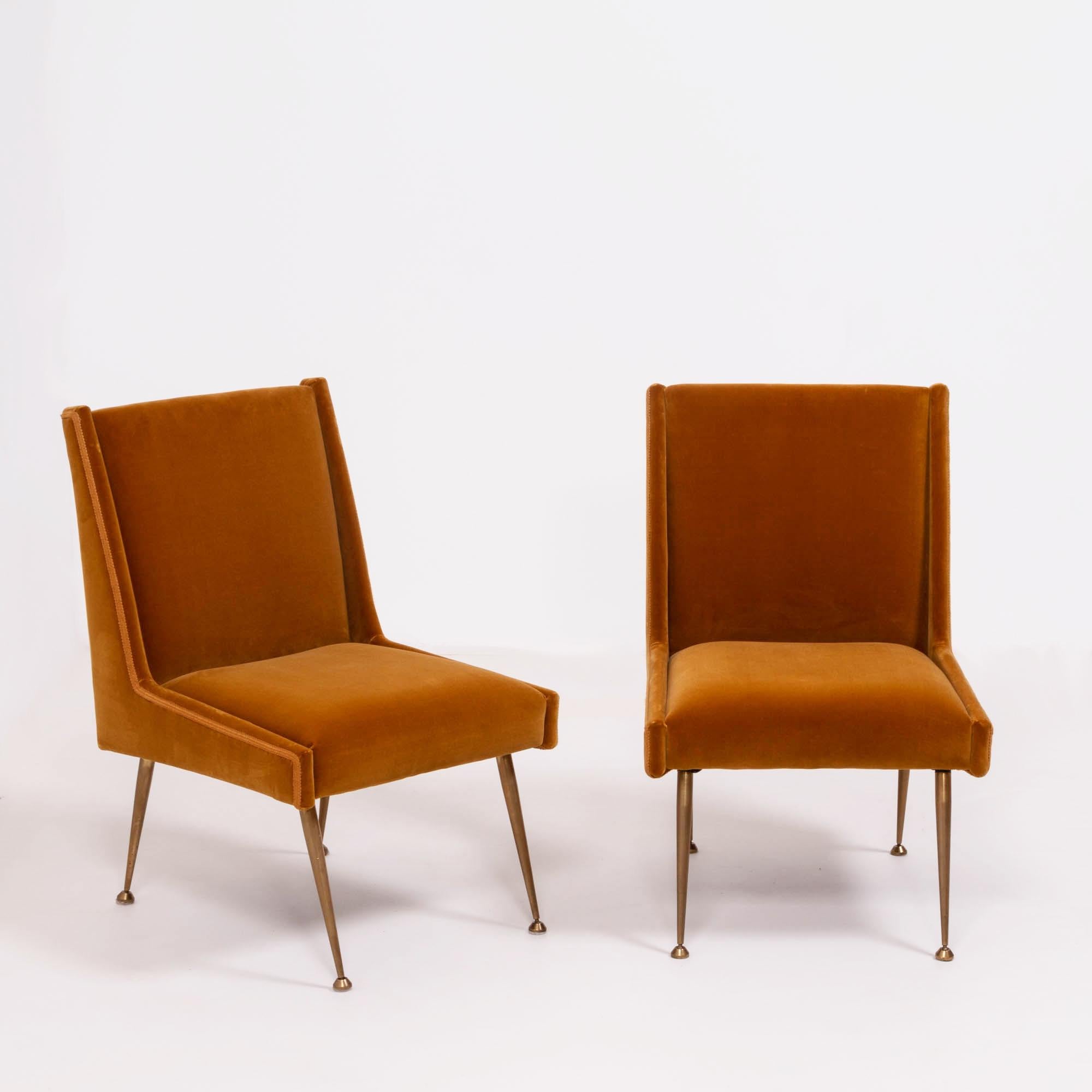 A beautifully designed pair of Mid Century chairs in burnt orange velvet, manufactured in Italy.

With a classic Italian silhouette, the chairs feature brass stiletto legs and a braided trim that complements the velvet.