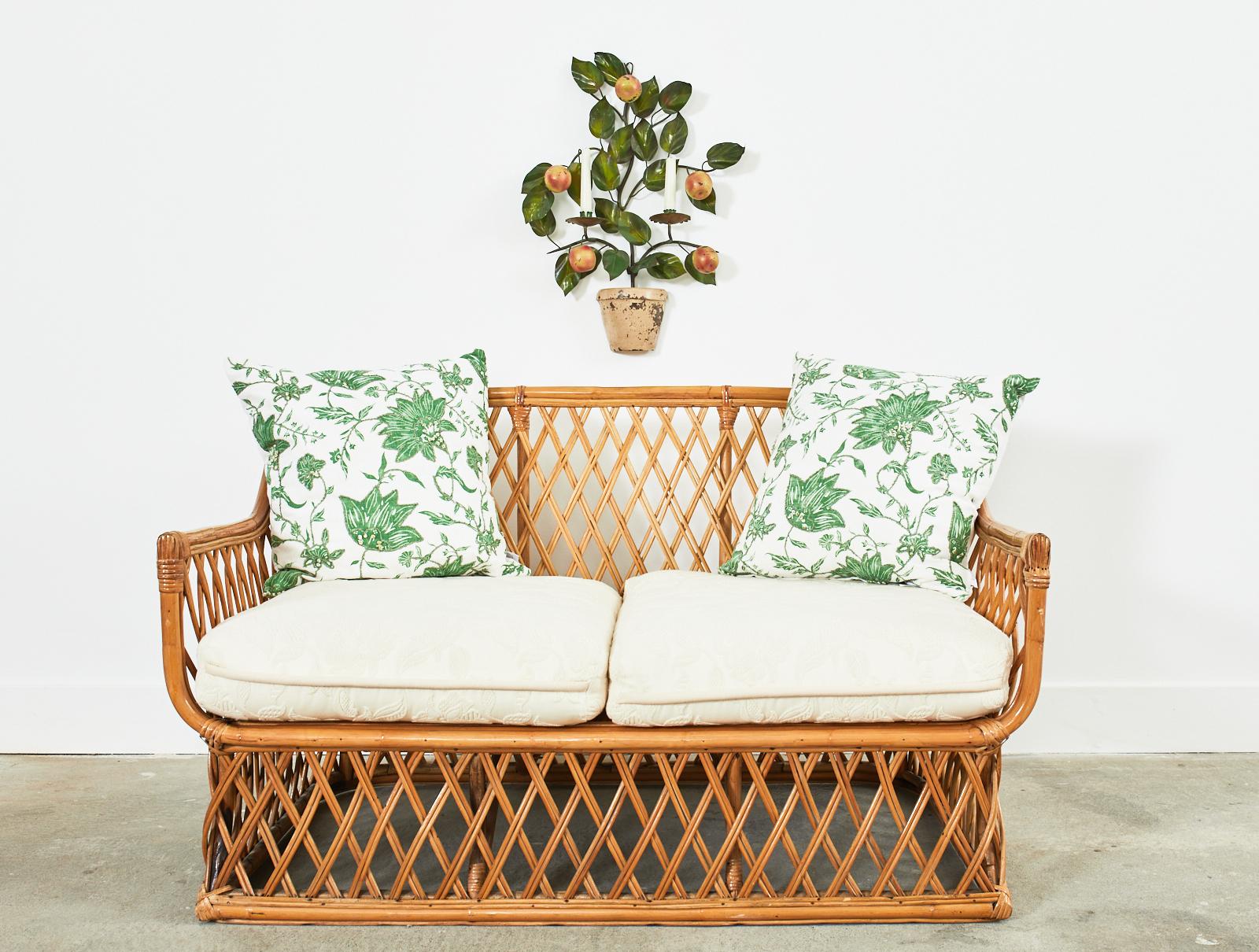 Charming mid-century Italian organic modern settee or loveseat hand-crafted from bamboo and rattan. The bamboo frame features geometric woven lattice sides and back constructed from pencil reed rattan. The back gracefully curves down to the arms and