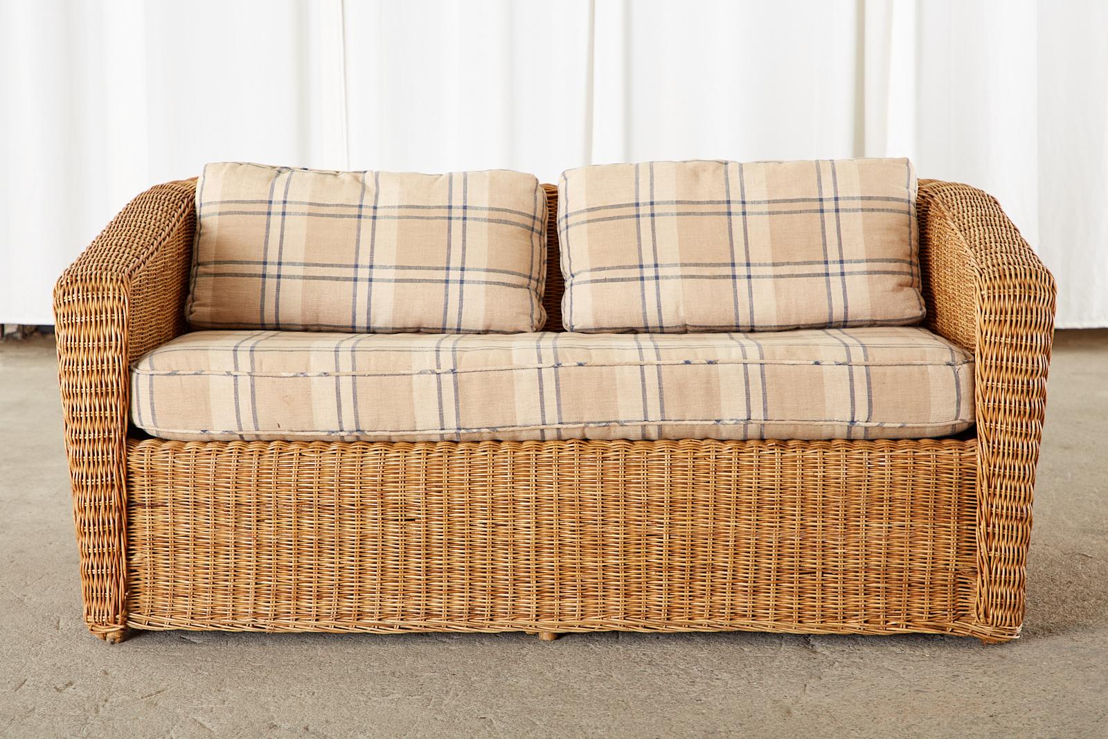 Distinctive Mid-Century Modern case loveseat shaped sofa featuring a rattan frame covered with woven wicker. Made in Italy in the organic modern style. The back and arms are slightly flared with a thick braided, flat border. Fitted with a loose seat
