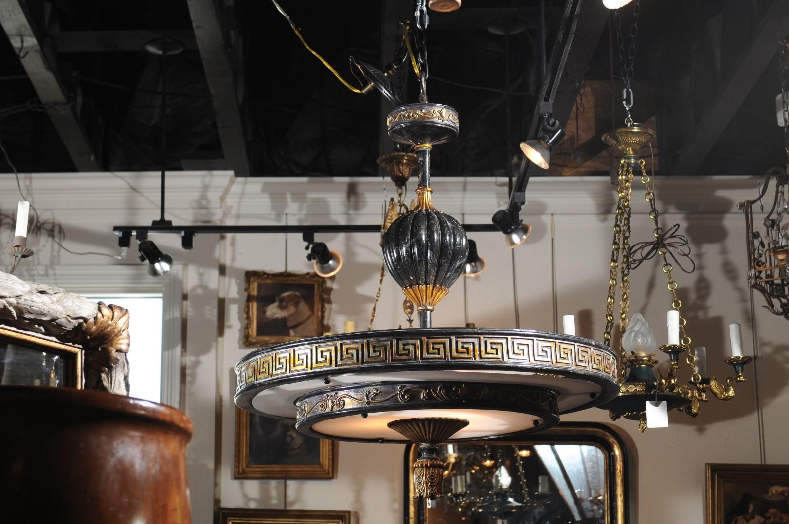 An Italian vintage carved wood parcel-gilt circular chandelier from the mid-20th century, with Greek key frieze and scrollwork motifs. Born in Italy during the midcentury period, this exquisite circular chandelier attracts all of our attention with