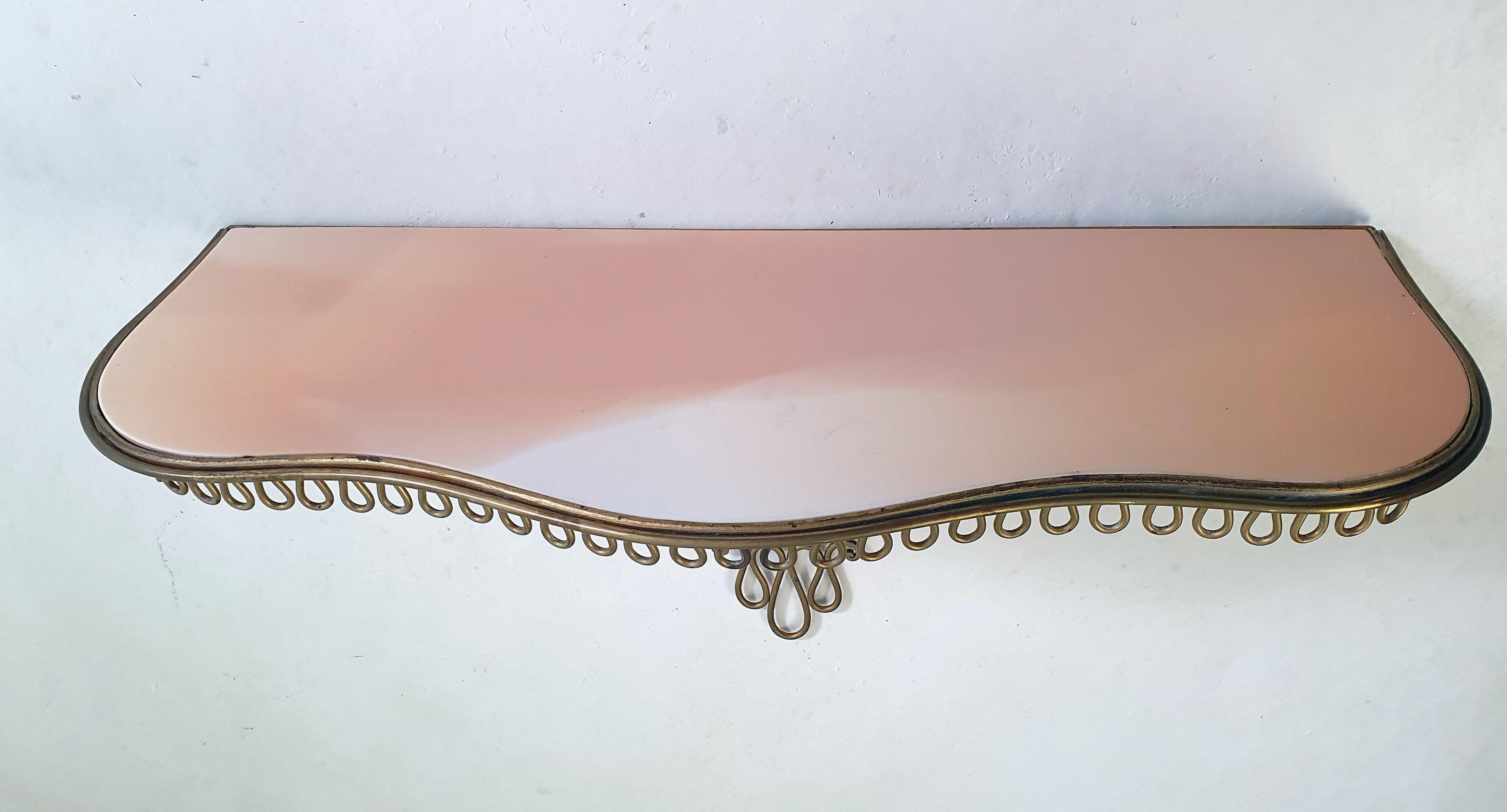 A lovely Italian console table in brass with a black glass top made in the 1950s. It is sturdy once mounted on the wall and in good condition. No cracks to the glass which has a wonderful peach pink tone.