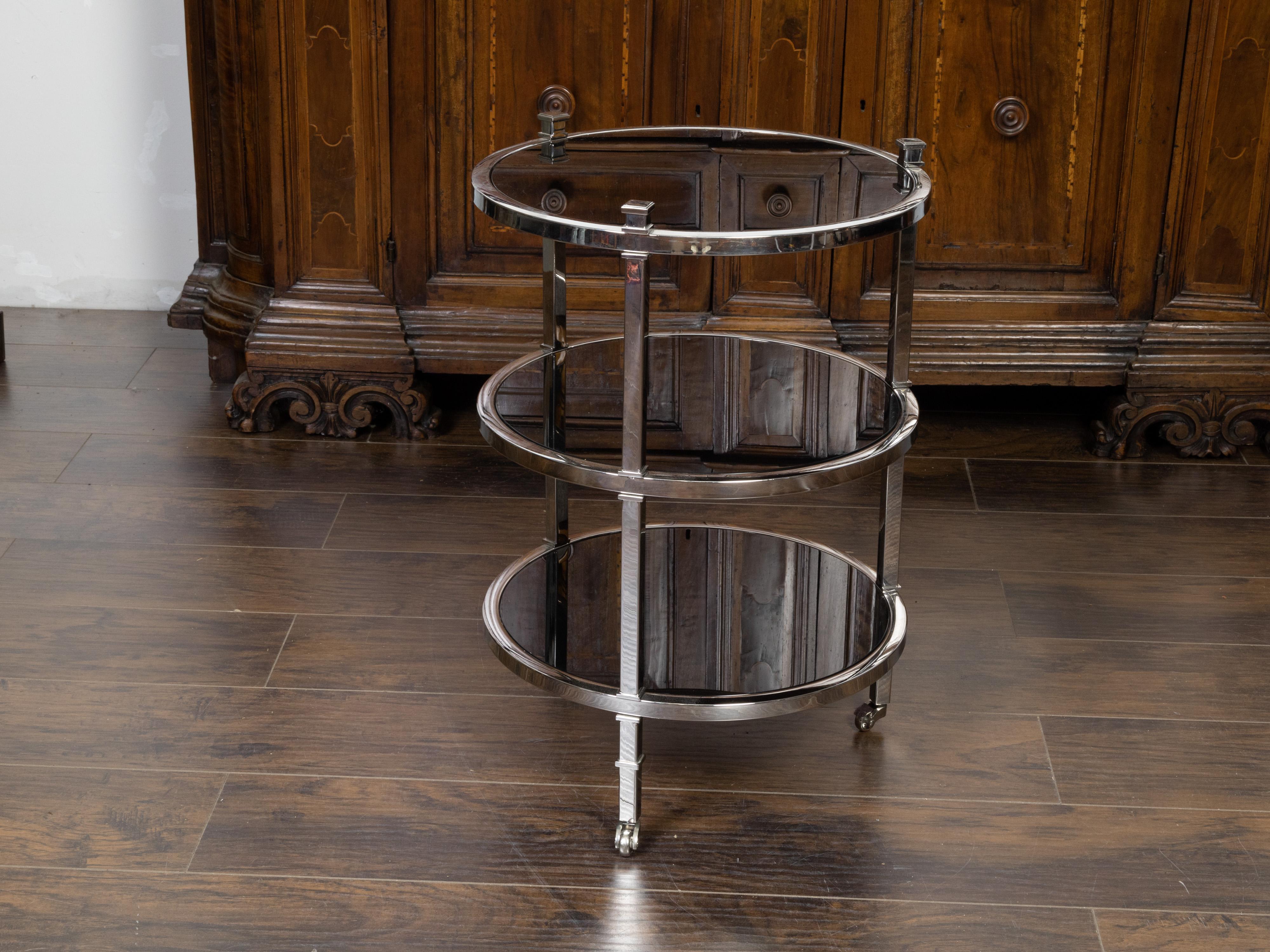 A vintage Italian polished nickel bar cart from the mid 20th century, with three circular shelves. Created in Italy during the midcentury period, this bar cart features three mirrored shelves secured within a polished nickel structure topped with