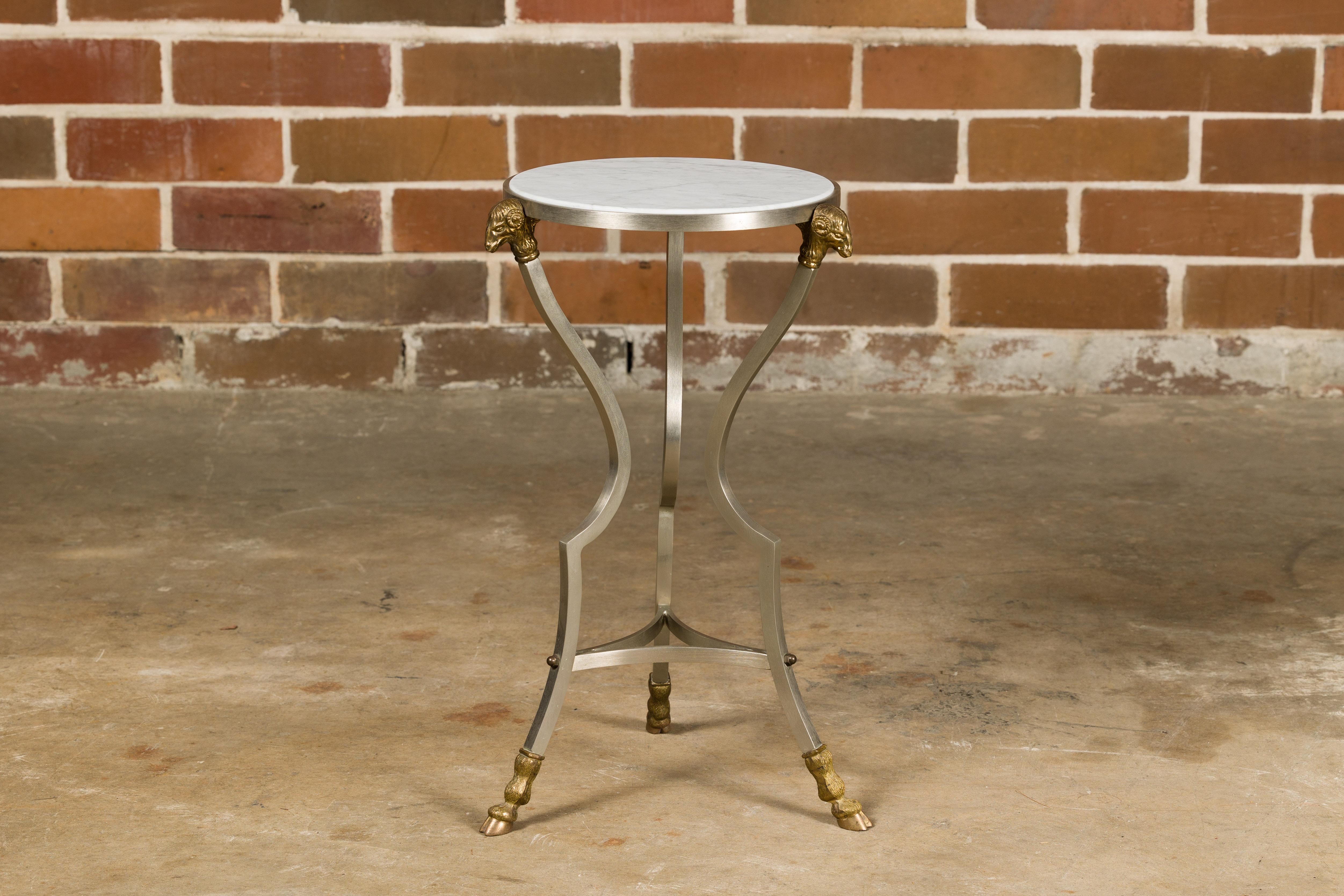 An Italian Midcentury steel side table with brass rams heads, hoofed feet and white marble top. This Italian Midcentury steel side table is an epitome of elegance and artistry, merging the sleekness of steel with the opulence of brass and marble.