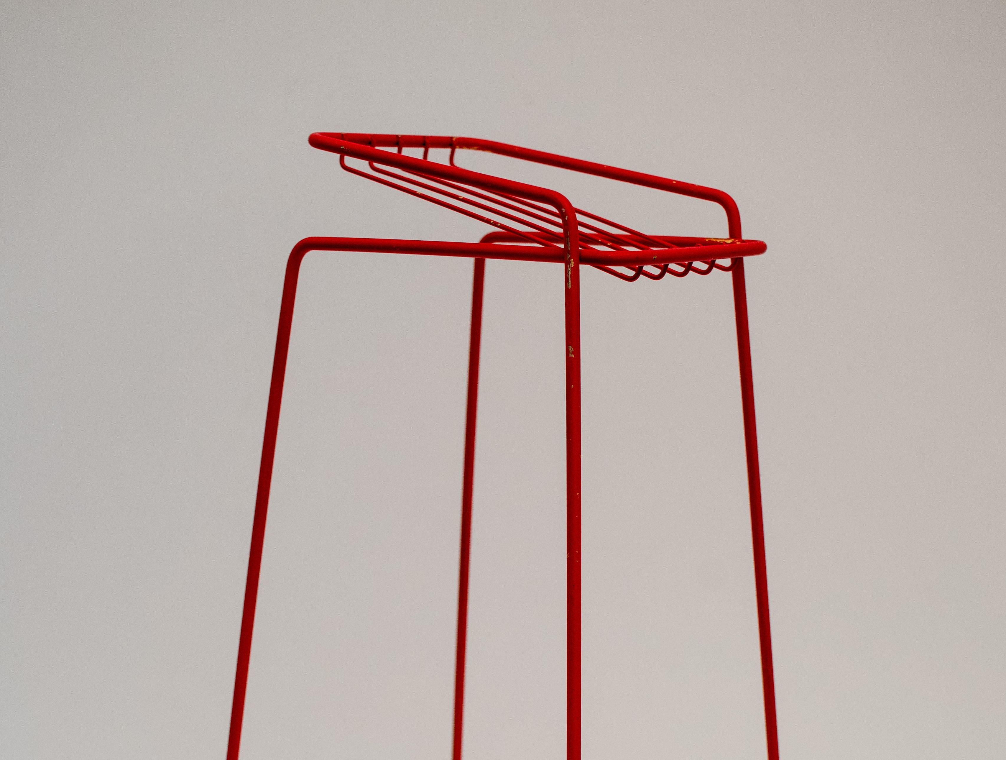 This narrow side table features a frame in red-lacquered steel produced in 1973.