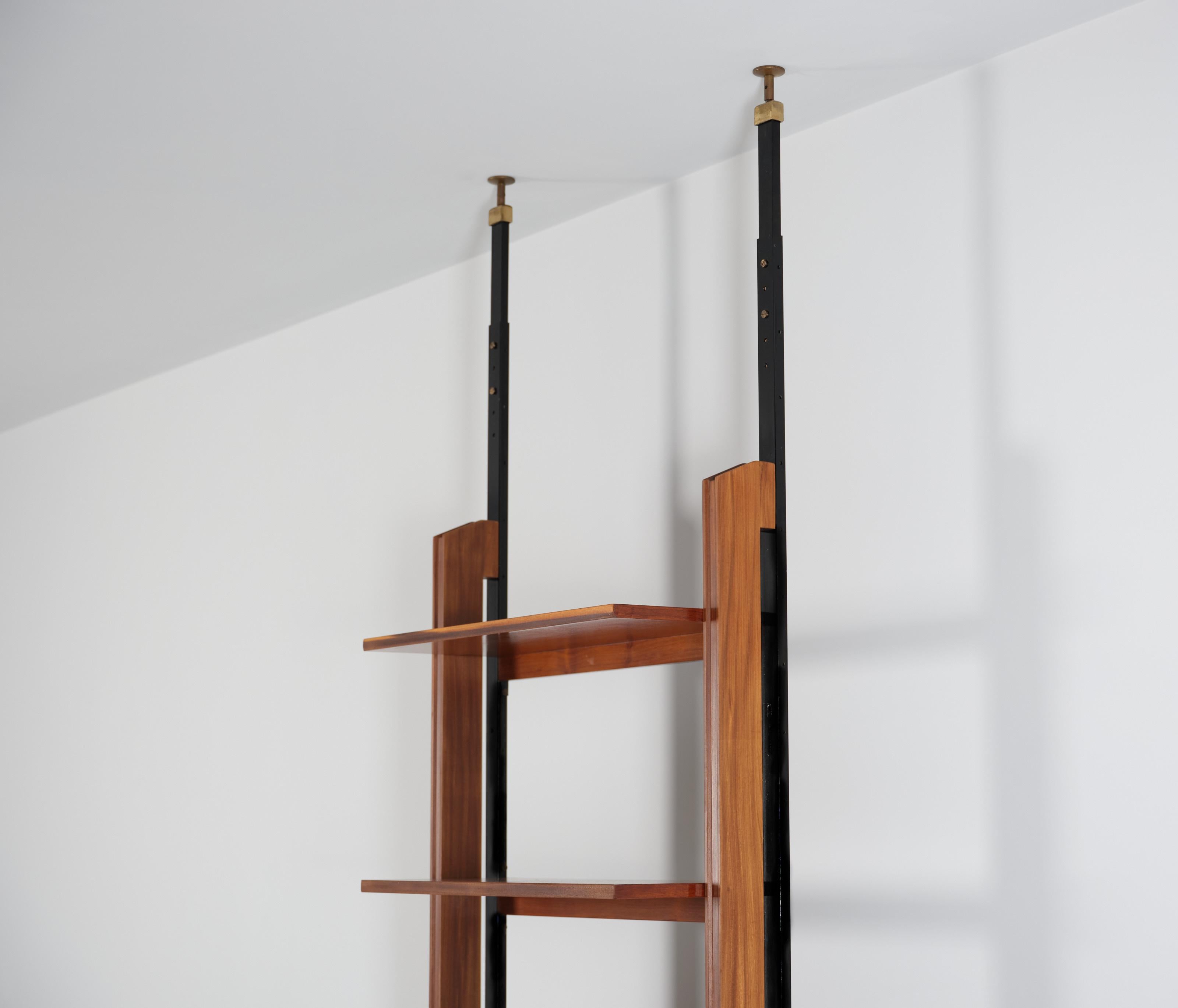 Crafted from the finest teak wood, this modular Wall Unit features a sophisticated system of pressure mounting between the floor and ceiling, ensuring stability and adaptability to any space. The combination of teak wood and iron creates a