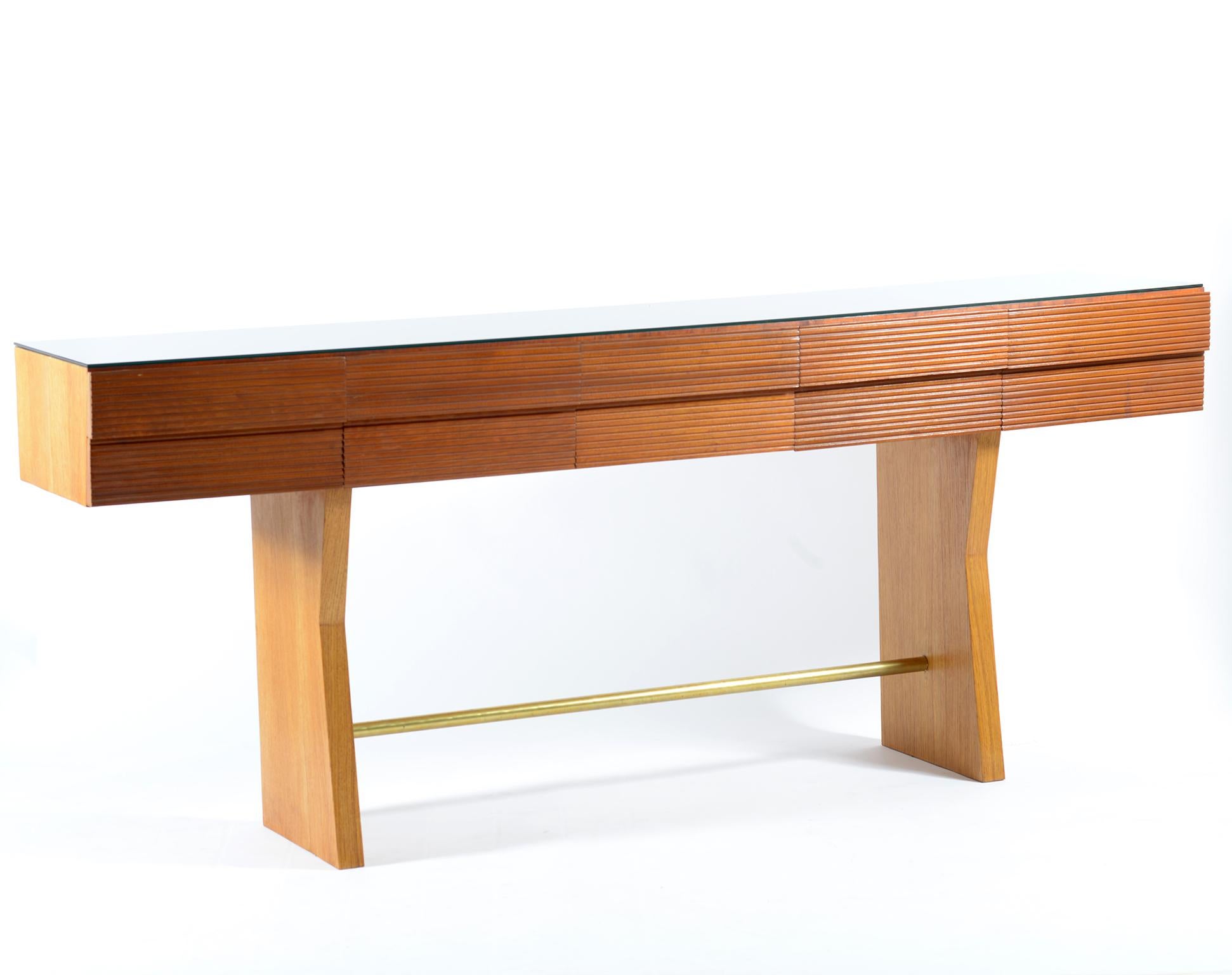 Elegant walnut console with ten grooved drawers, the top is a black glass.
The two side legs are connected by a brass bar.
This piece of furniture can be considered also a chest of drawer.
Italia Mid-Century Modern, 1950.