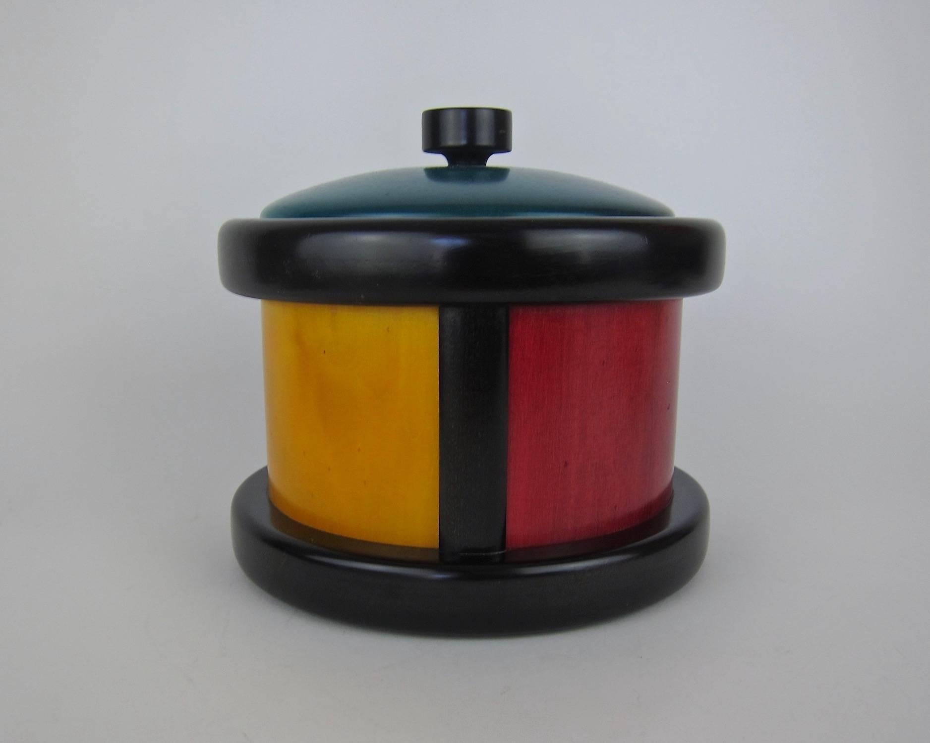 A colorful midcentury woodenware ice bucket designed by Pietro Manzoni for Vietri of Bergamo, Italy. The vintage ice bucket was hand-made of Italian wood and decorated with bold color blocked panels in golden yellow, teal green, and dark red, framed